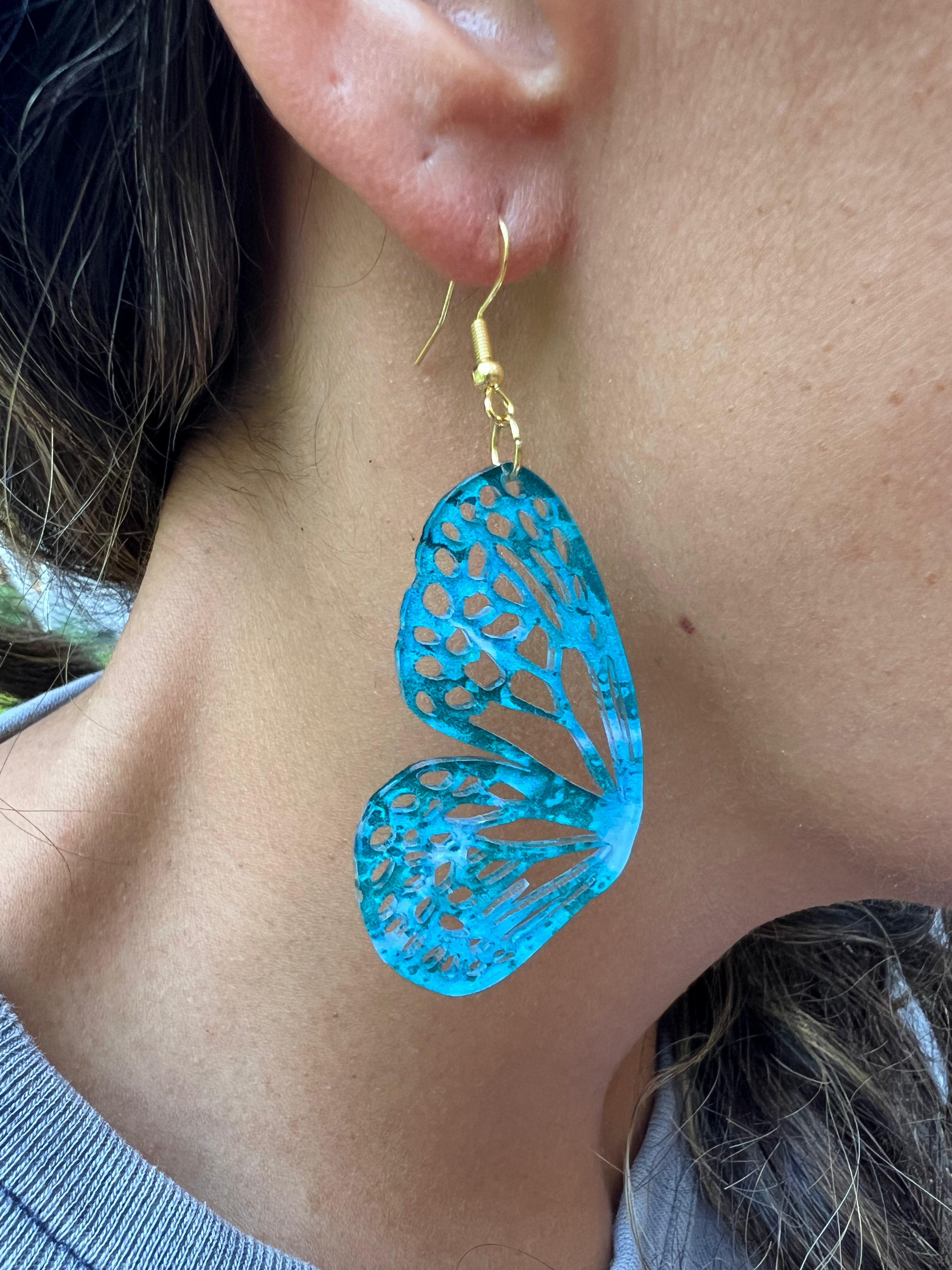 Blue butterfly-shaped earrings worn by a person