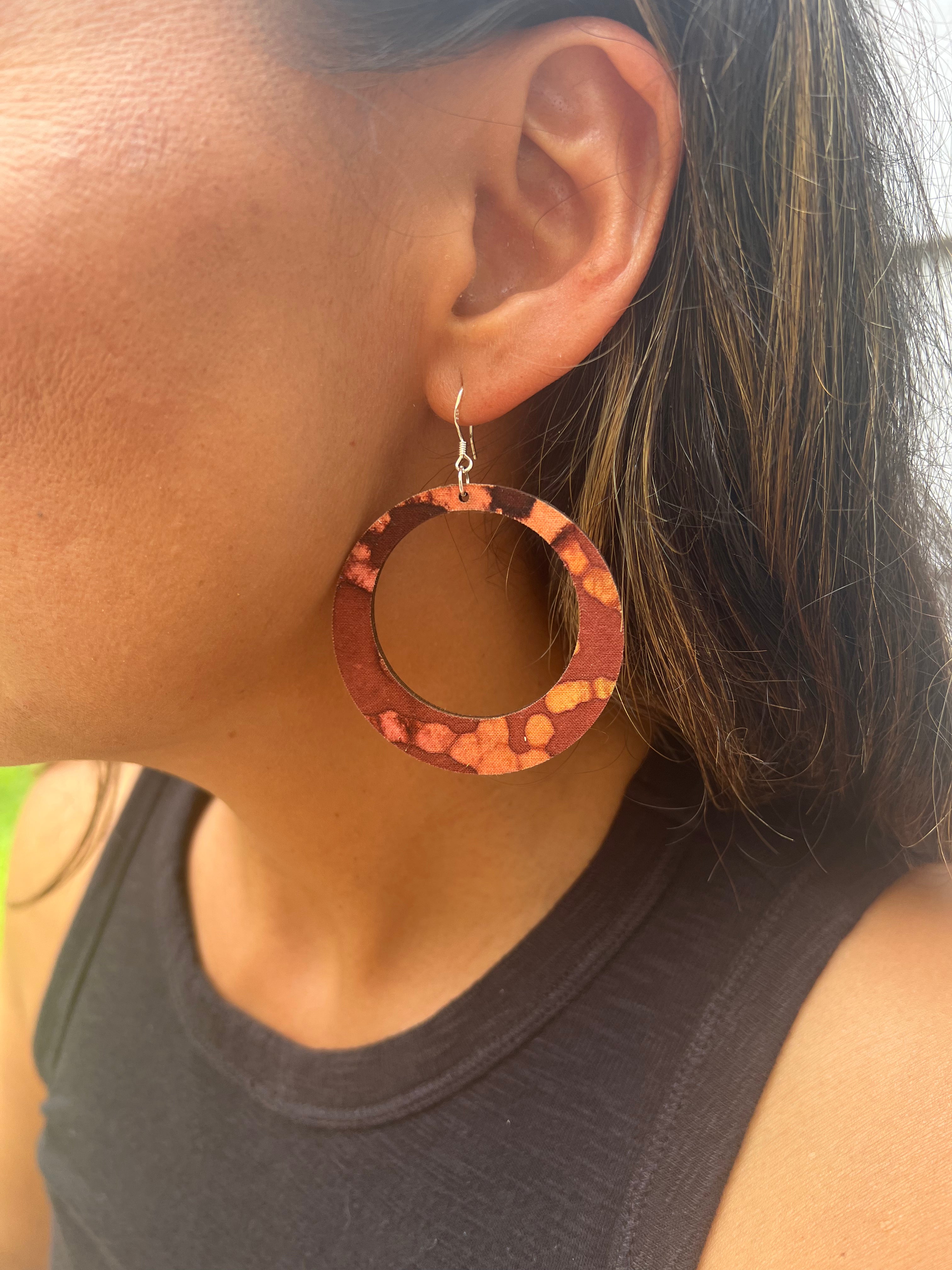 Close-up of a person wearing a hoop earring with a textured design.