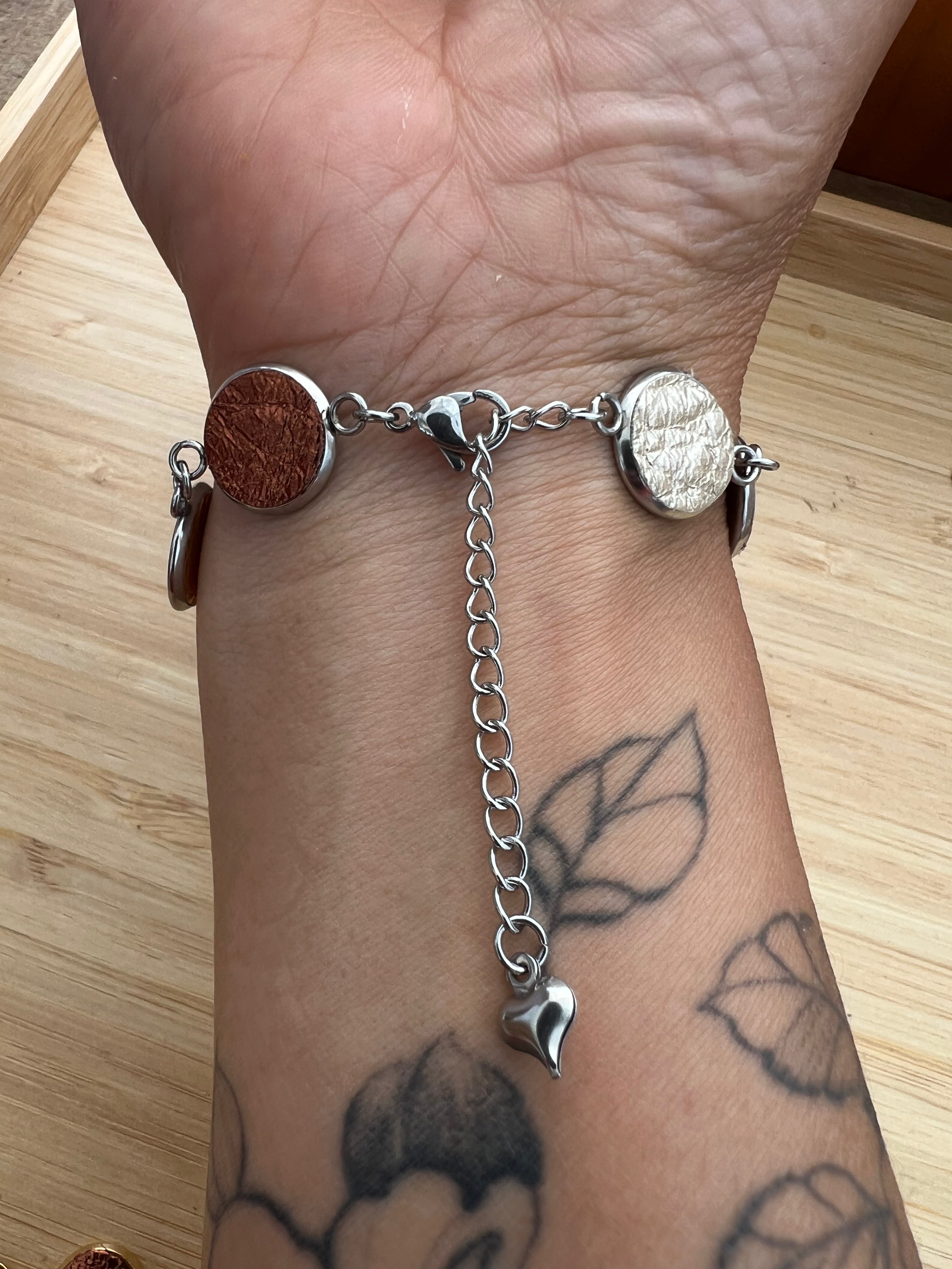 Everlink bracelet with a heart-shaped charm on a wrist with tattoos.