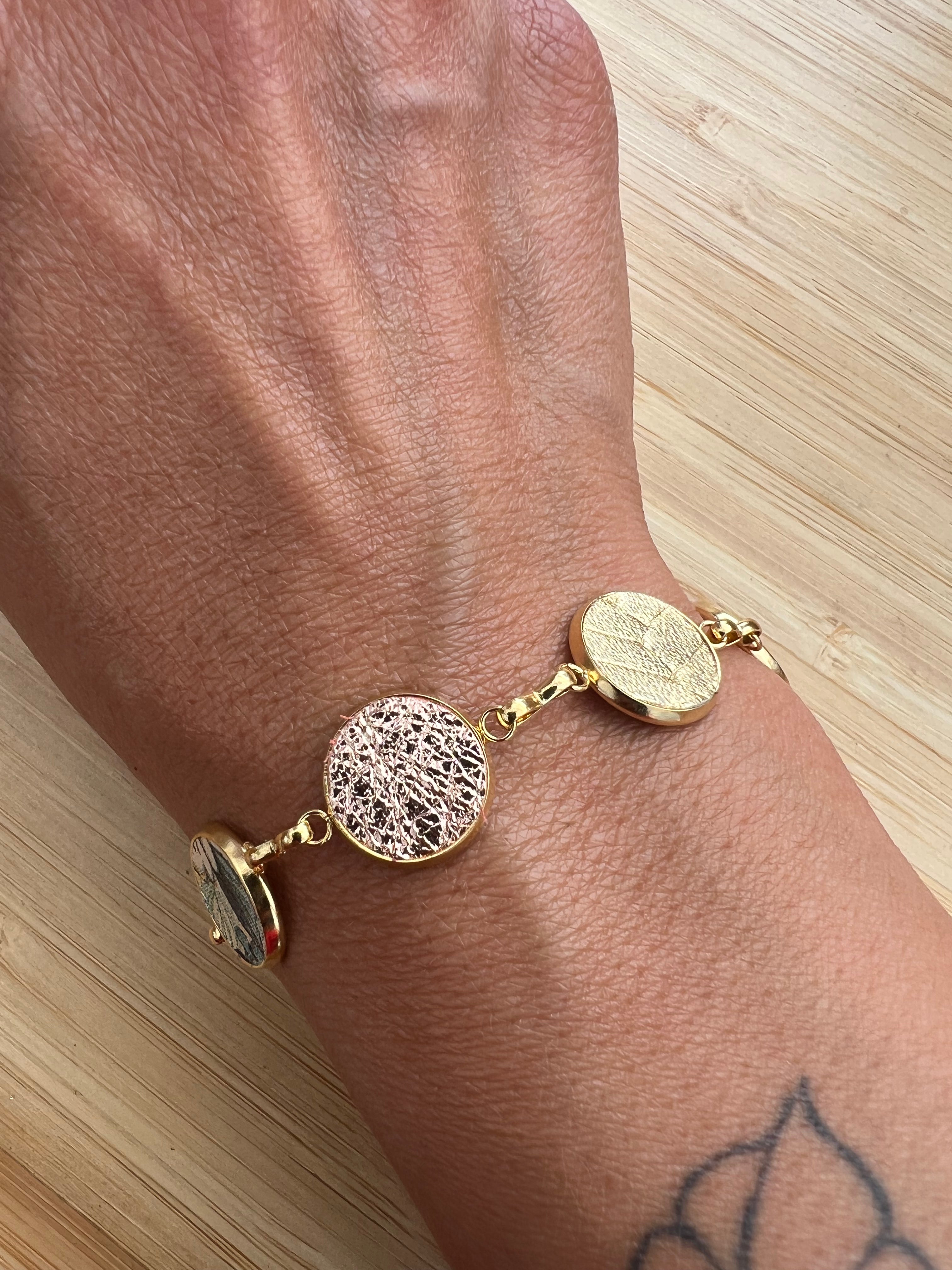 Everlink gold bracelet on a wrist against a light wooden background
