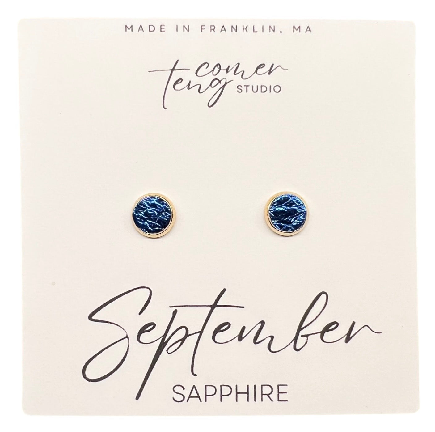 Pair of blue earrings on a card with 'September Sapphire' text and branding.