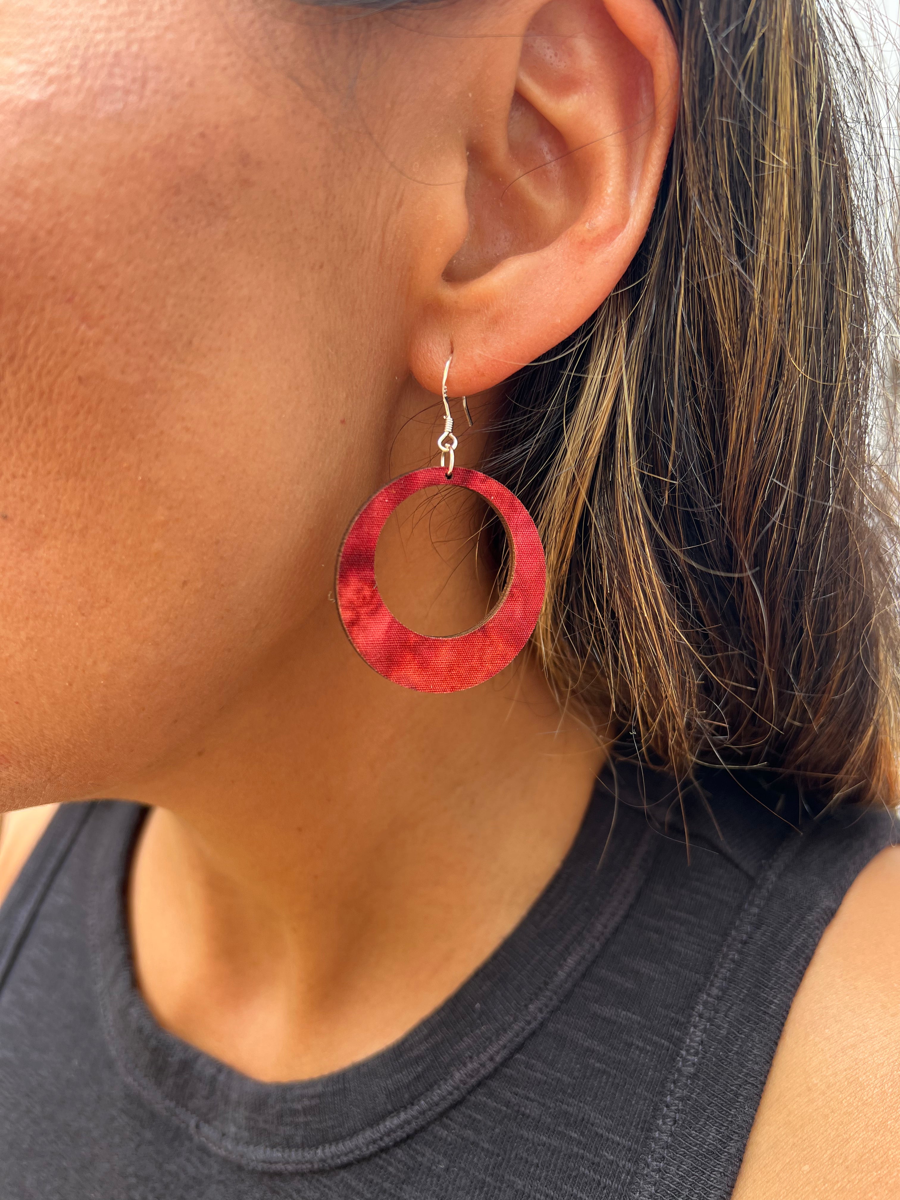 Red hoop earrings worn by a person with a neutral background