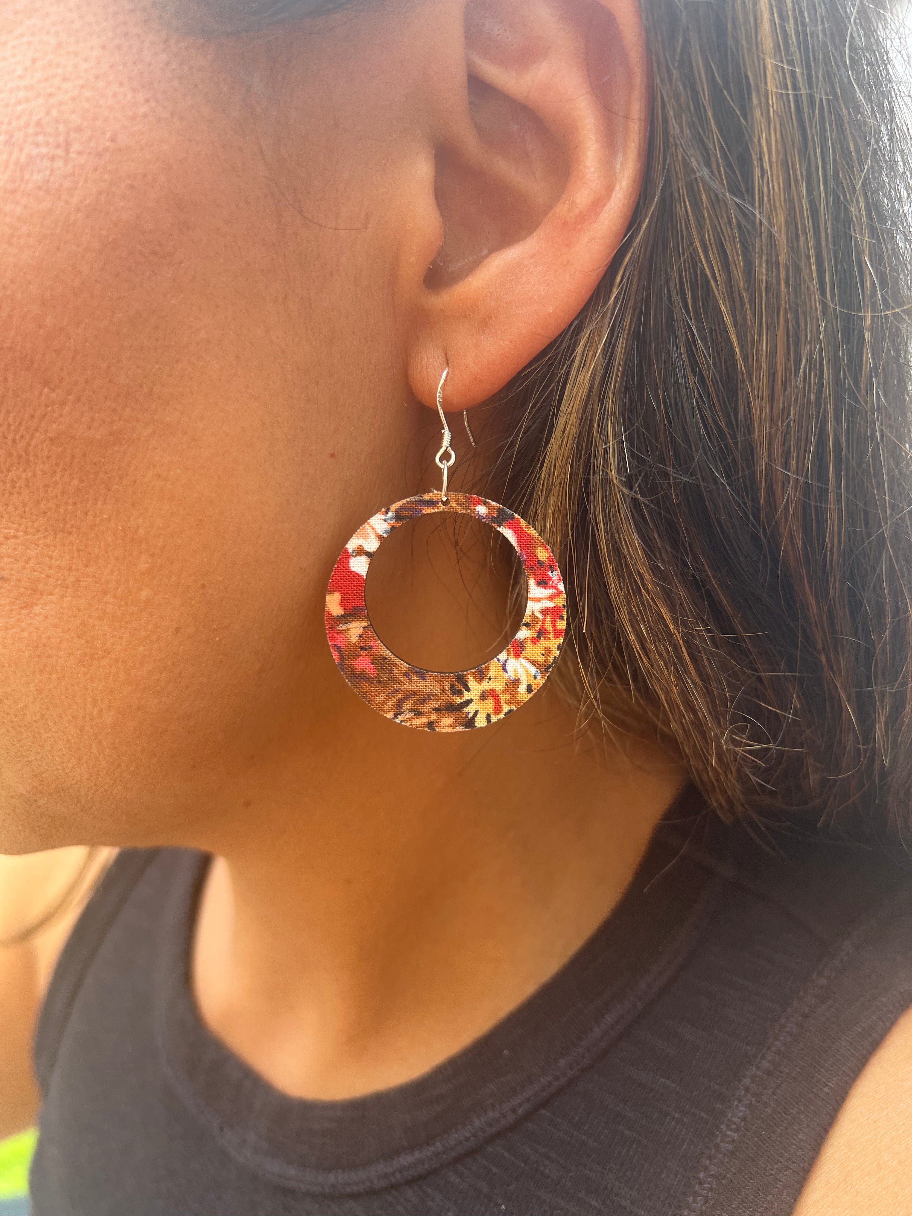 Close-up of a person wearing a floral hoop earring.