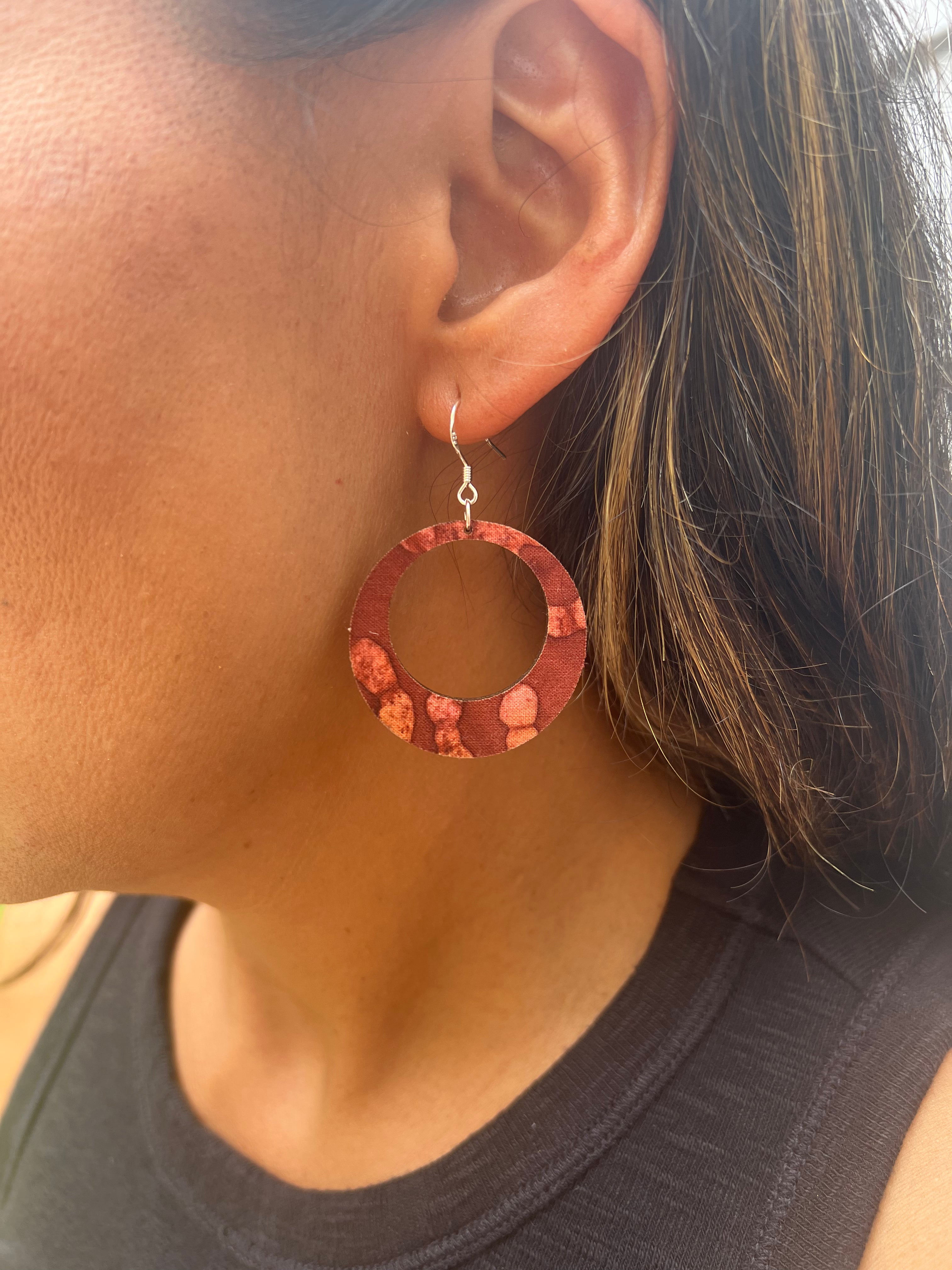 Close-up of a person wearing a brown floral hoop earring.