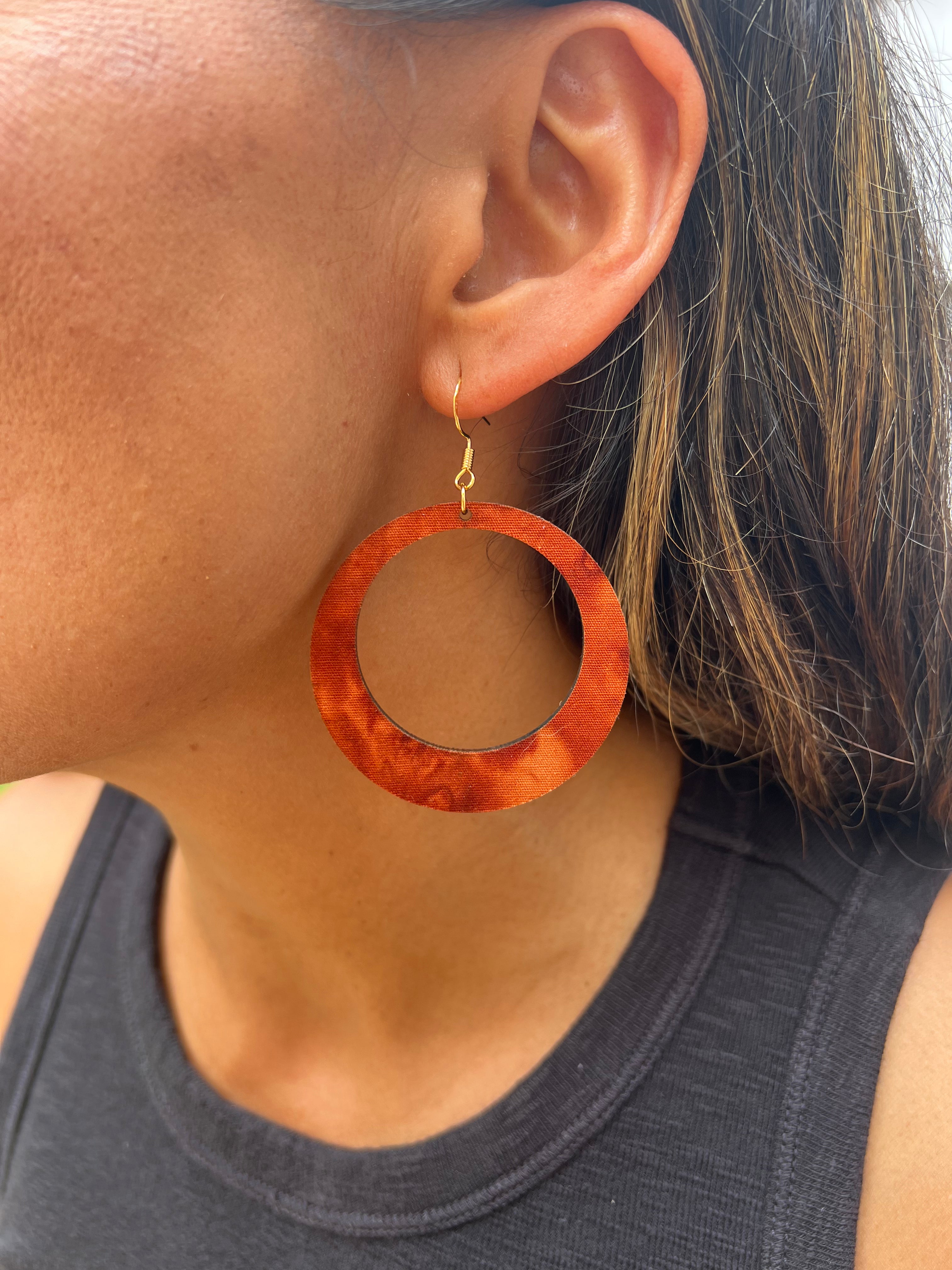 Close-up of a person wearing a large hoop earring with a dark background