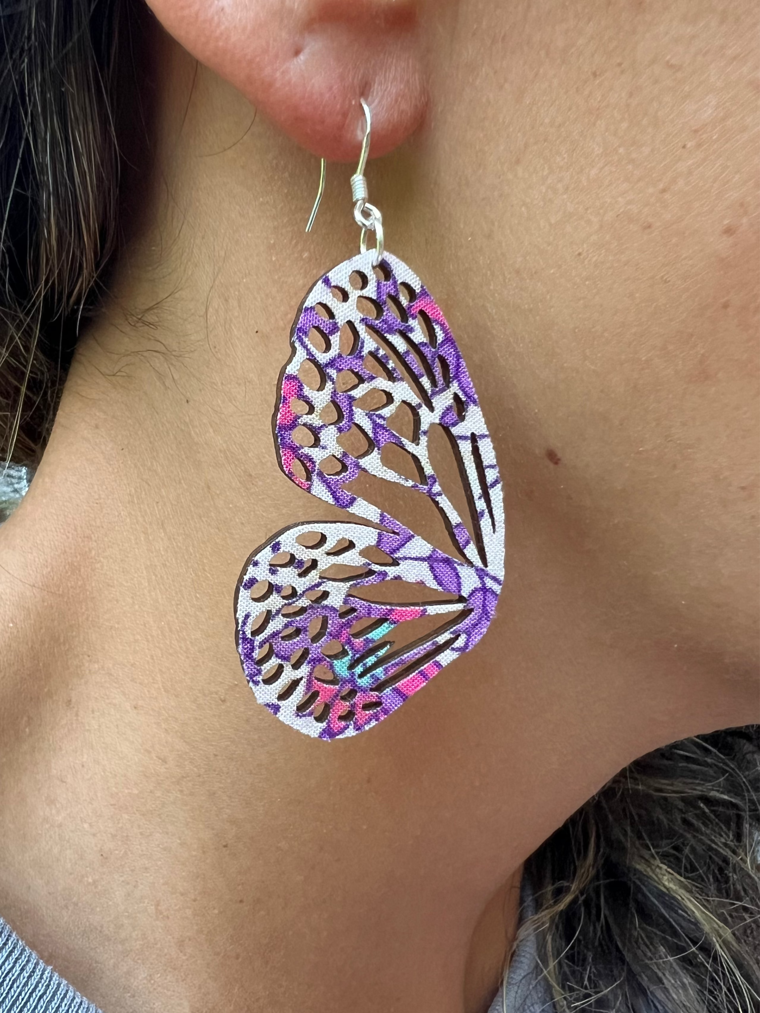 Close-up of a person wearing a colorful butterfly-shaped earring.