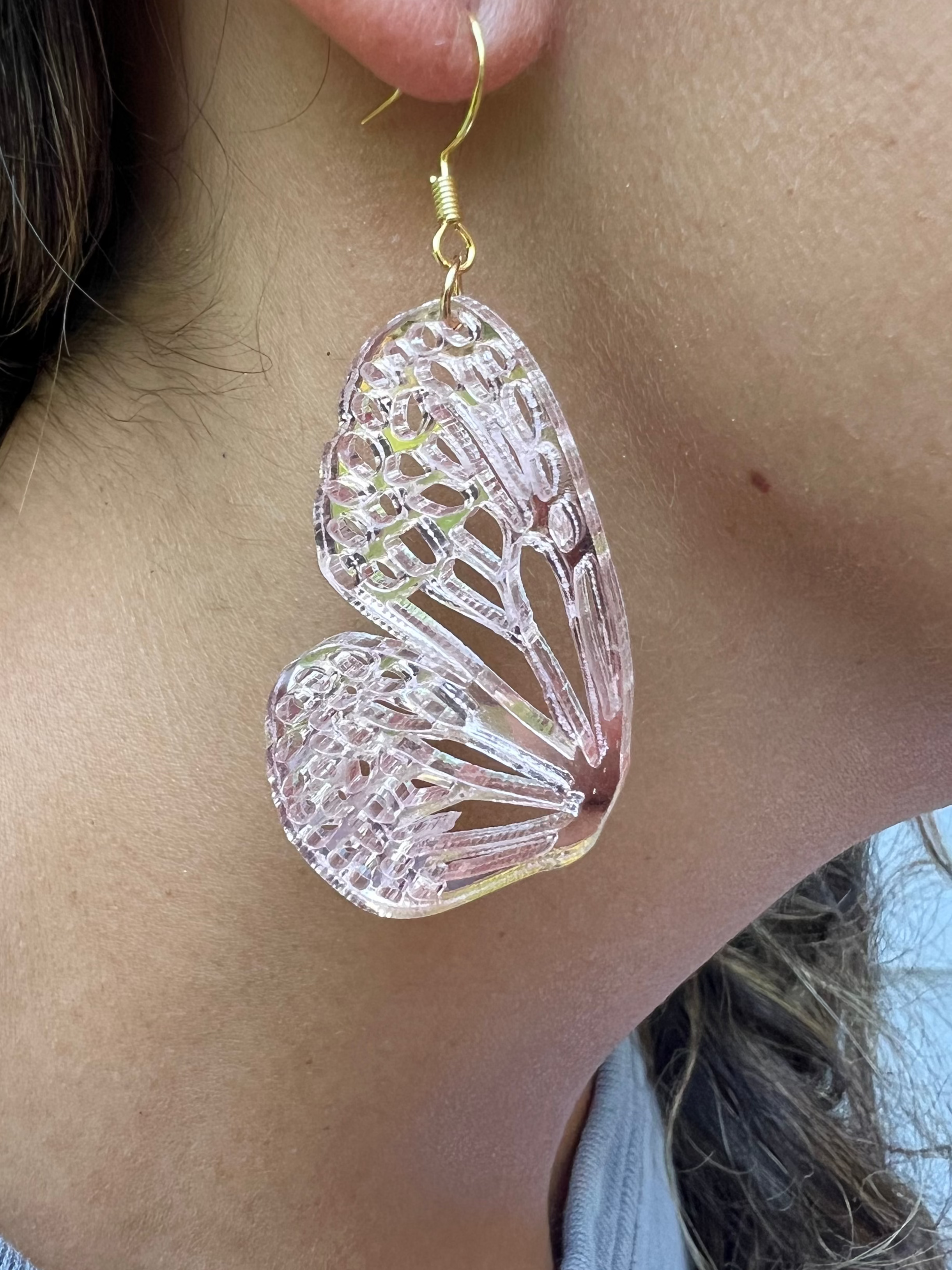 Close-up of a person wearing a translucent butterfly-shaped earring.
