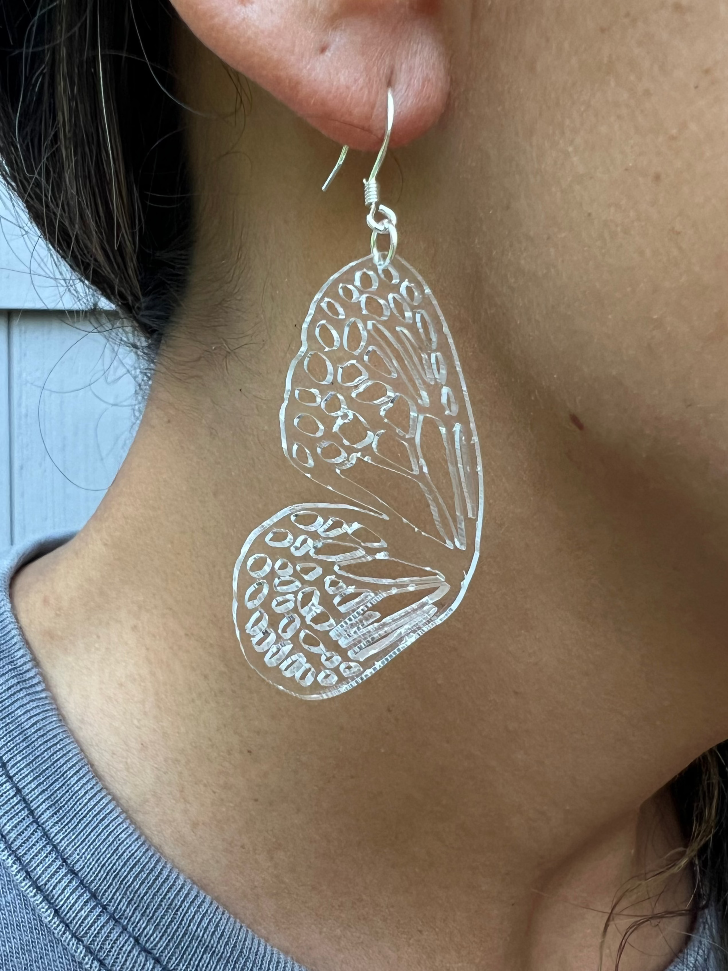 Close-up of a person wearing clear butterfly earring.