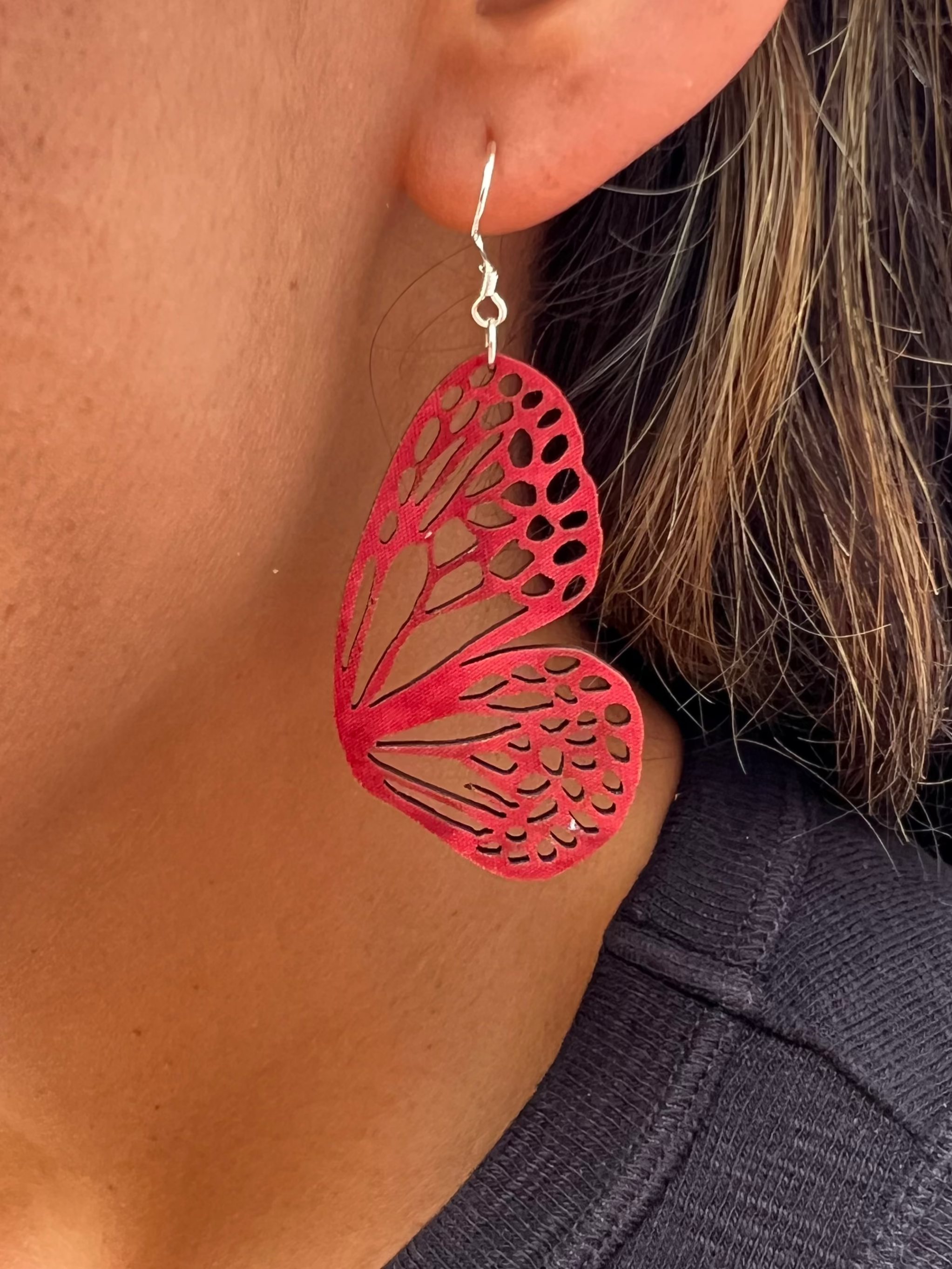 Cranberry butterfly-shaped earrings worn by a person