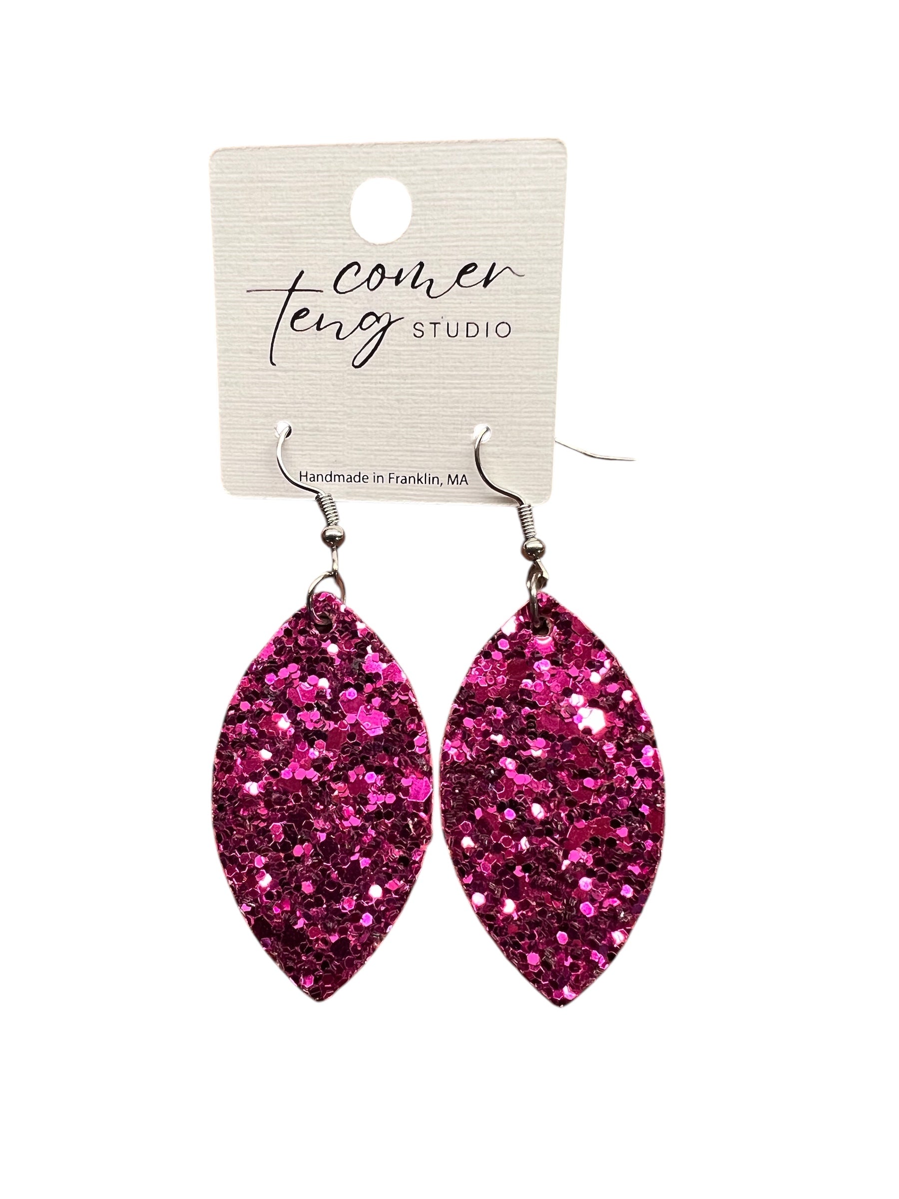 Pink glitter earrings on a Comer Teng Studio card against a white background