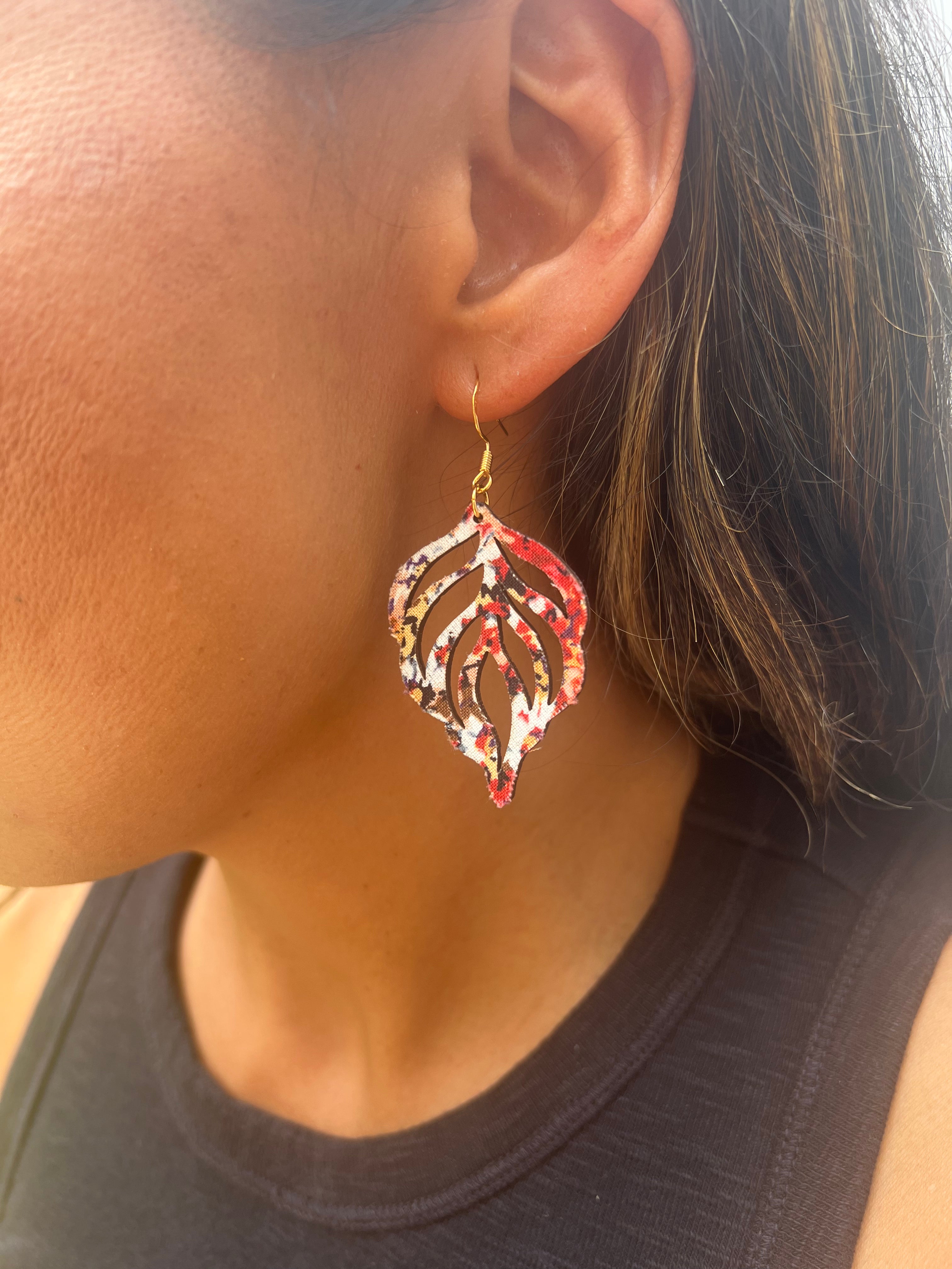 Close-up of a person wearing a decorative earring with a brown top background