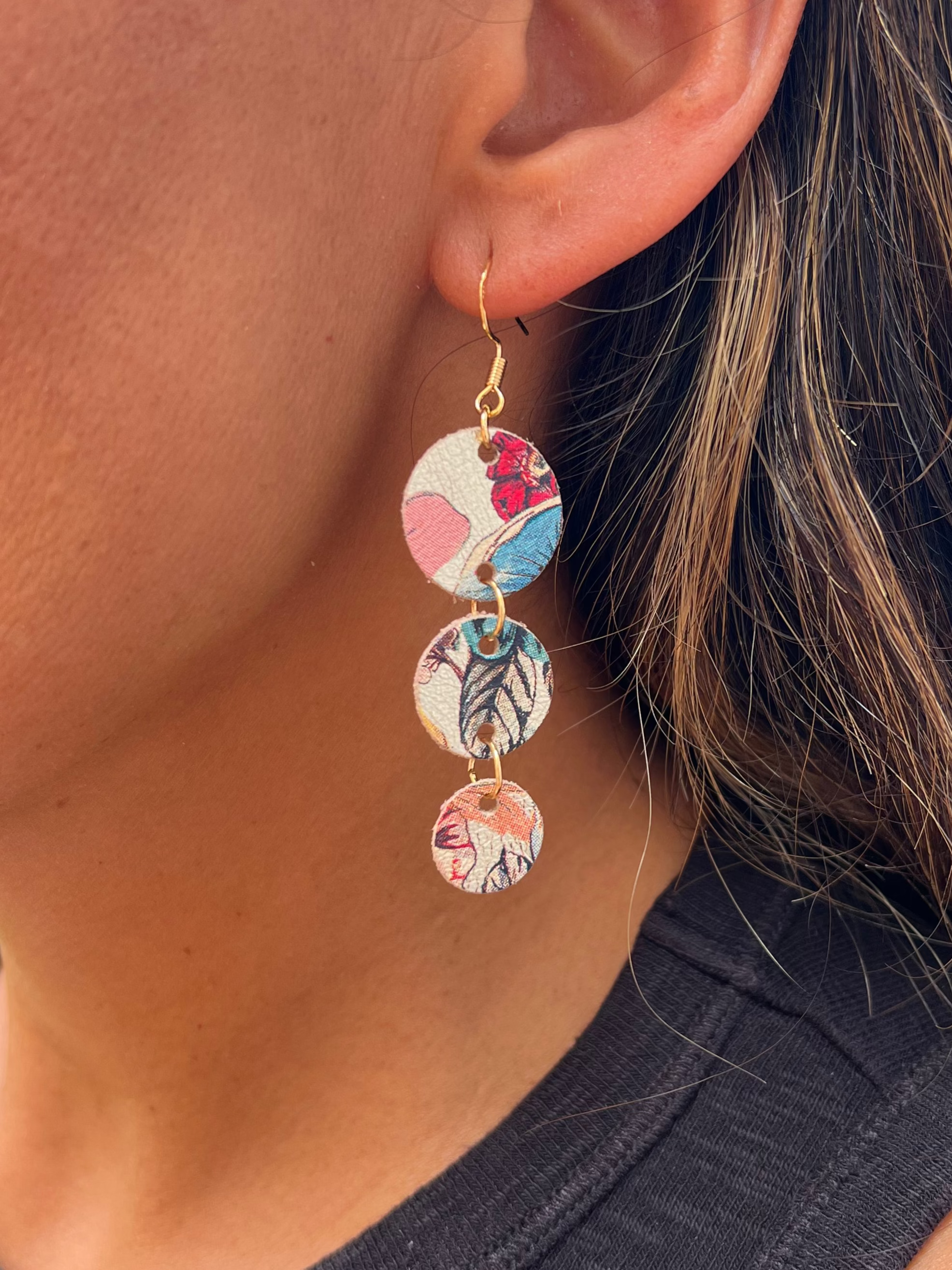 Close-up of a person wearing colorful circular earrings.