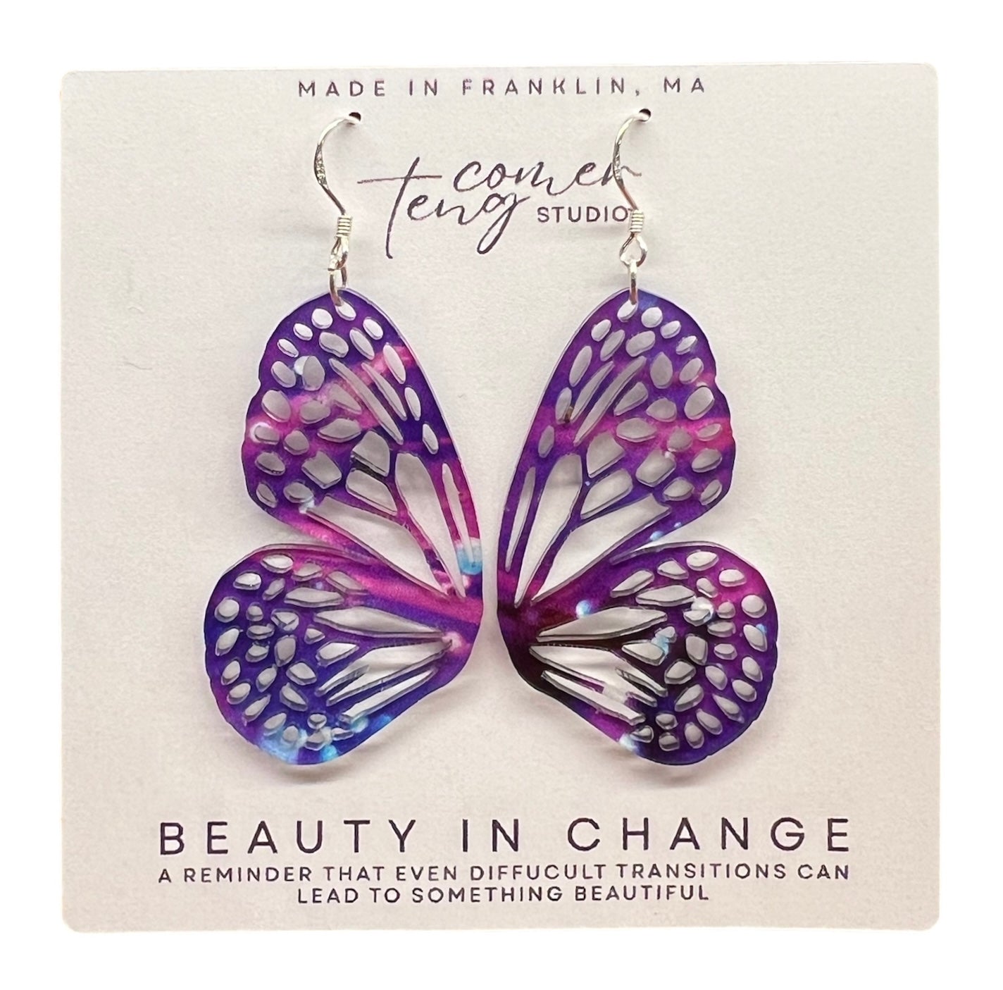 Butterfly-shaped earrings on a card with Beauty in Change.