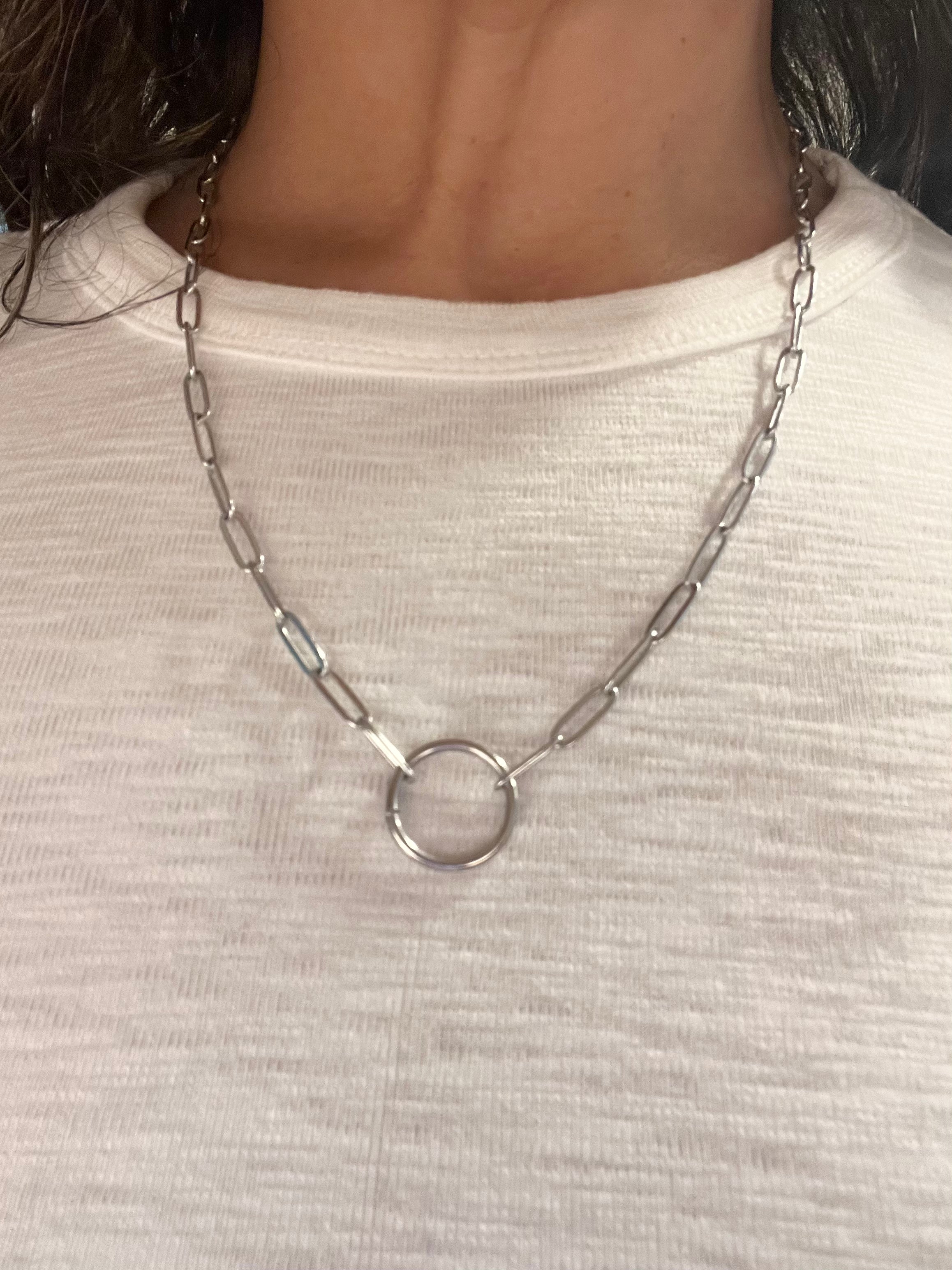 Silver chain necklace with a circular pendant on a white shirt