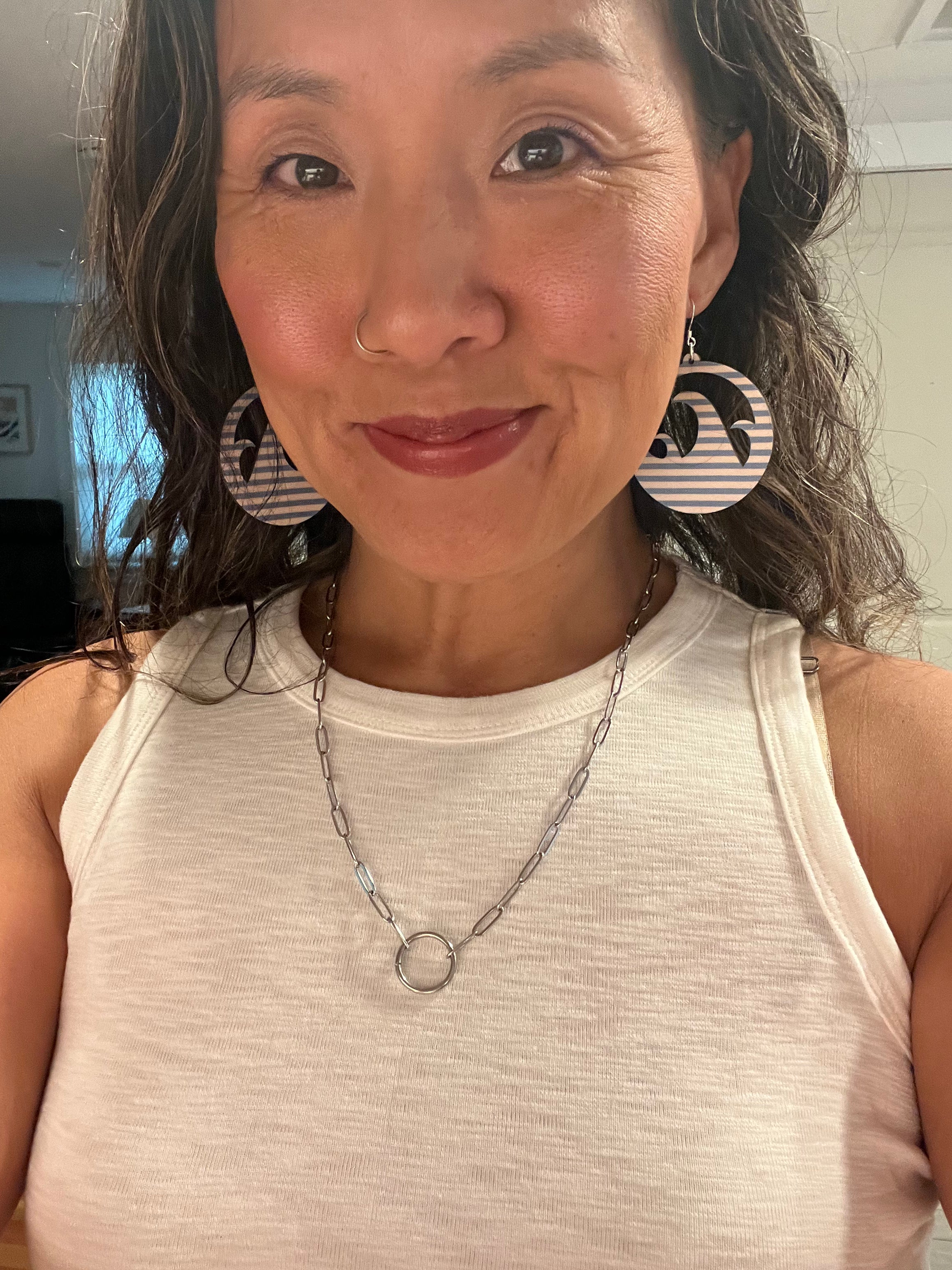 Woman wearing large circular earrings and a necklace indoors.
