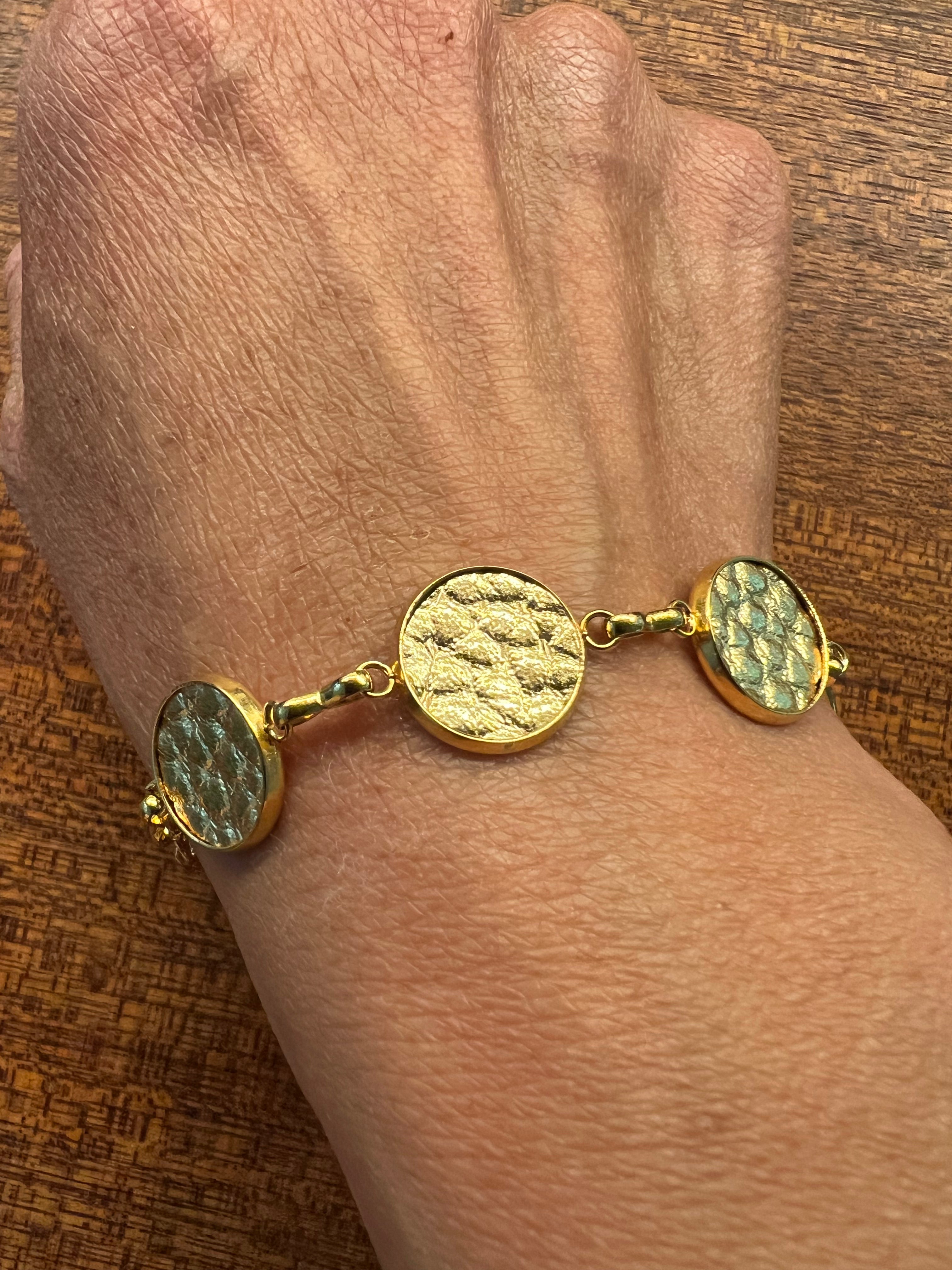 Gold bracelet with textured discs on a wrist against a wooden background