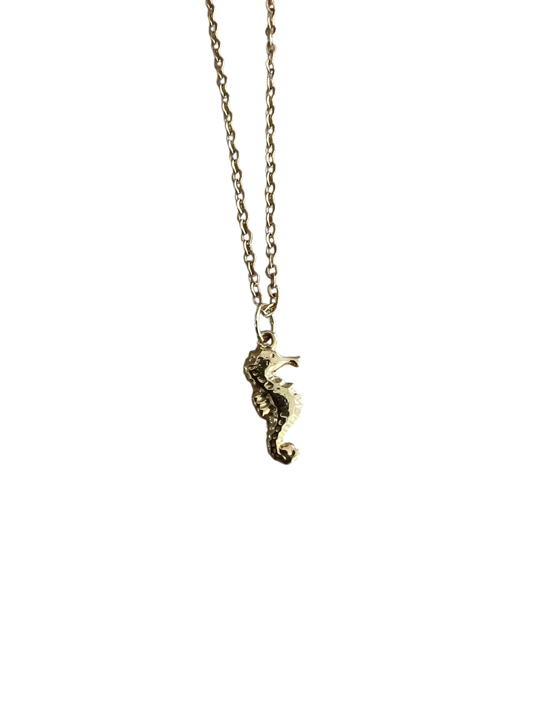 Gold seahorse necklace on a white background