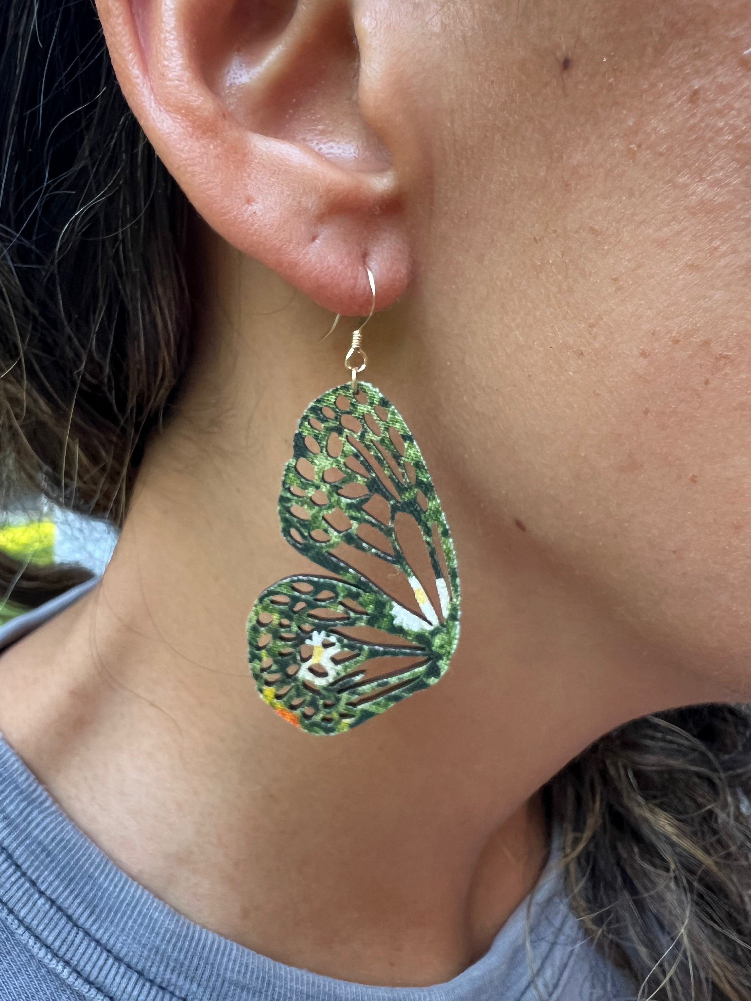 Close-up of a person wearing a green butterfly-shaped earring.