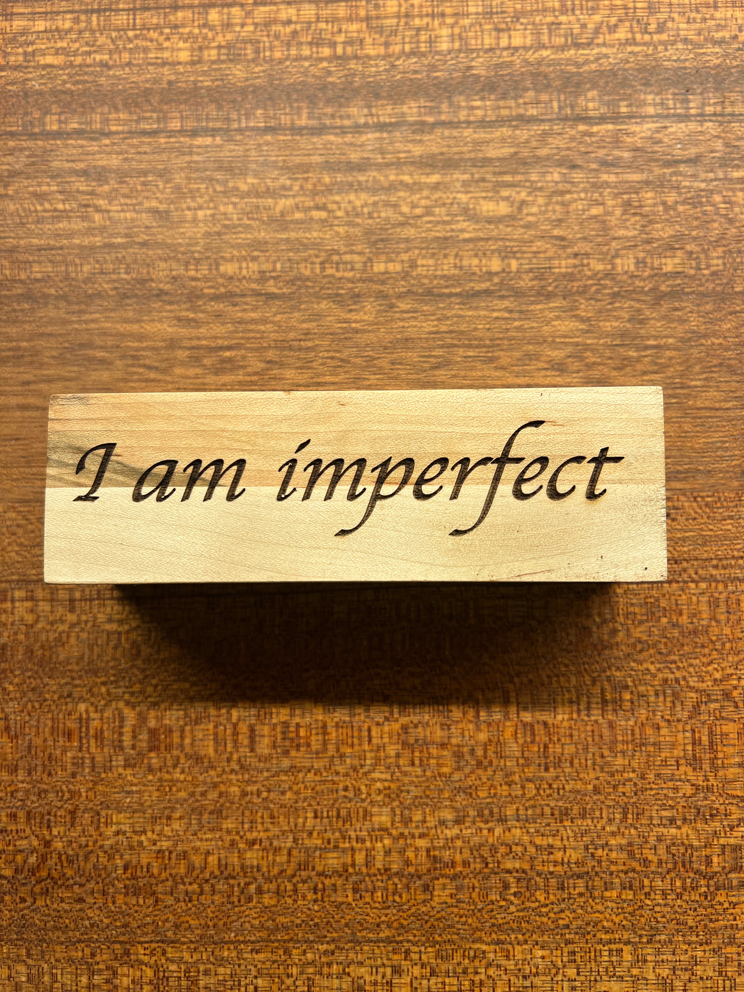 Wooden block with 'I am imperfect' text on a wooden background