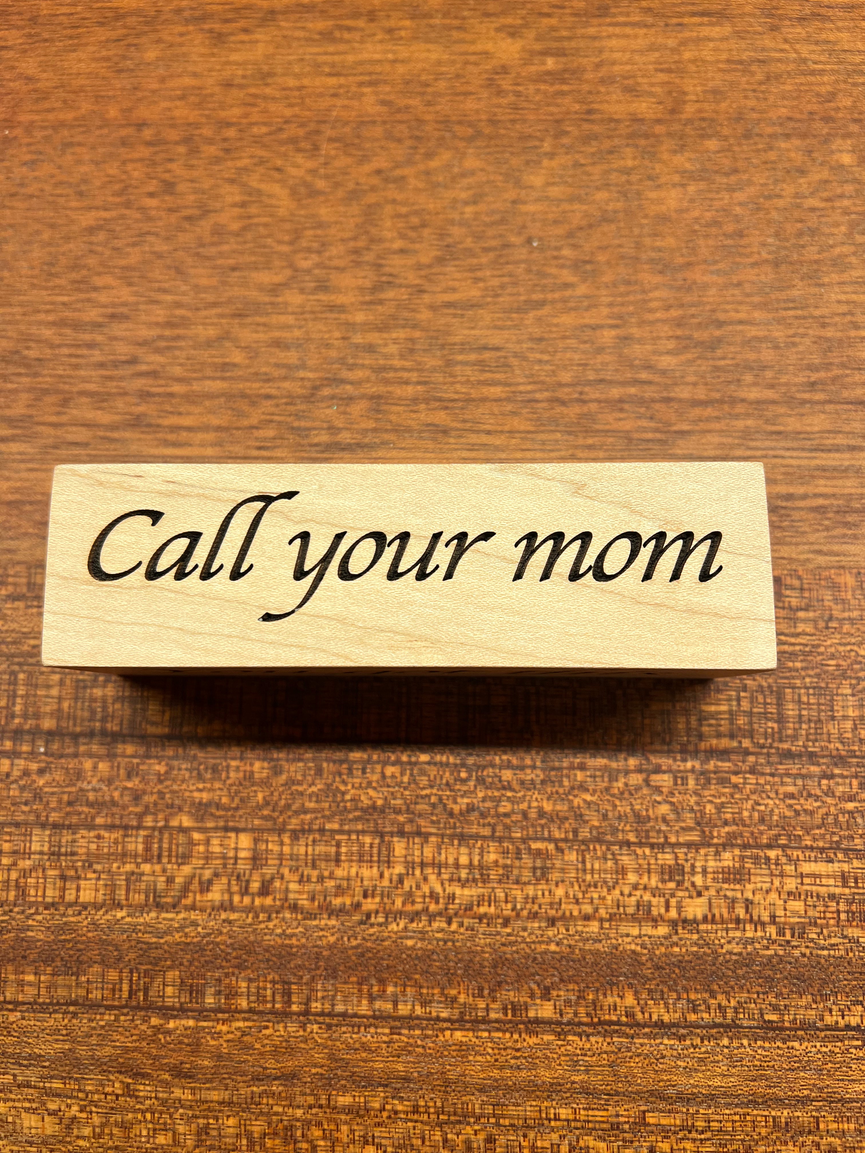 Wooden block with 'Call your mom' text on a wooden background