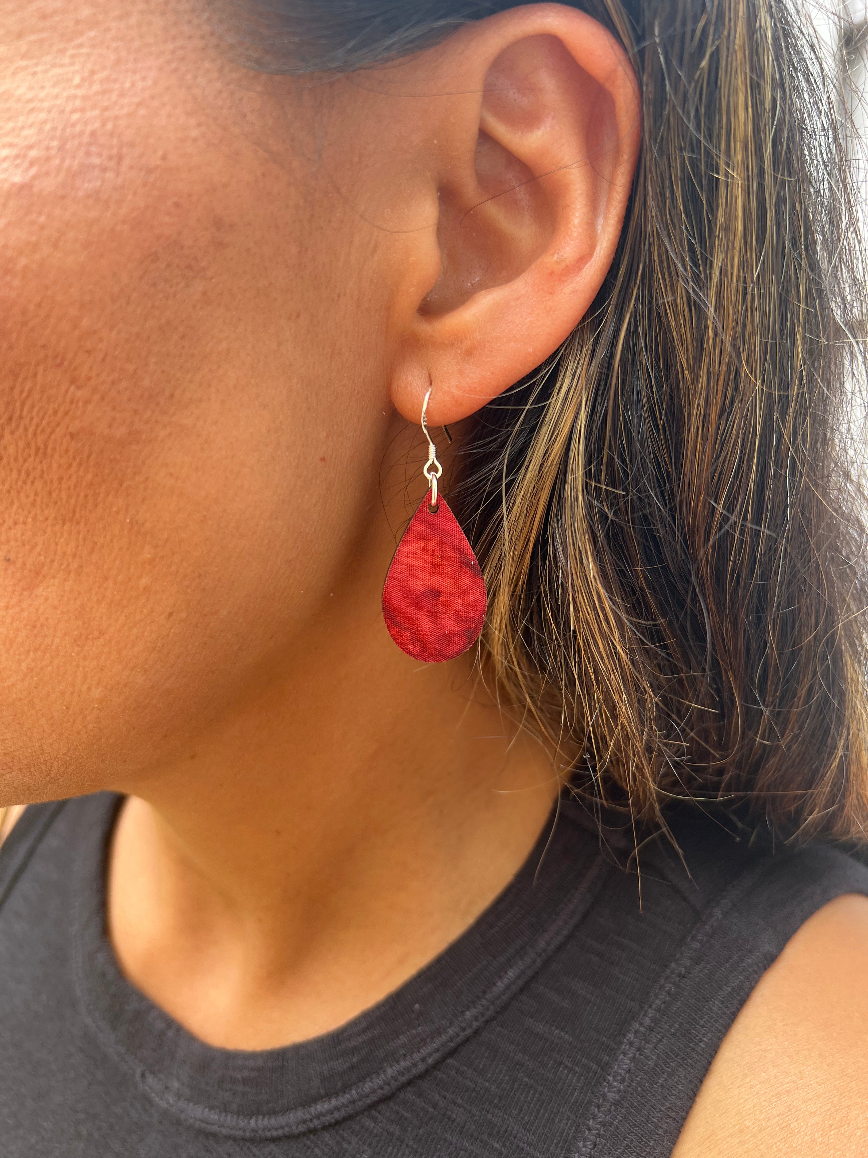 Close-up of a person wearing red teardrop earrings.
