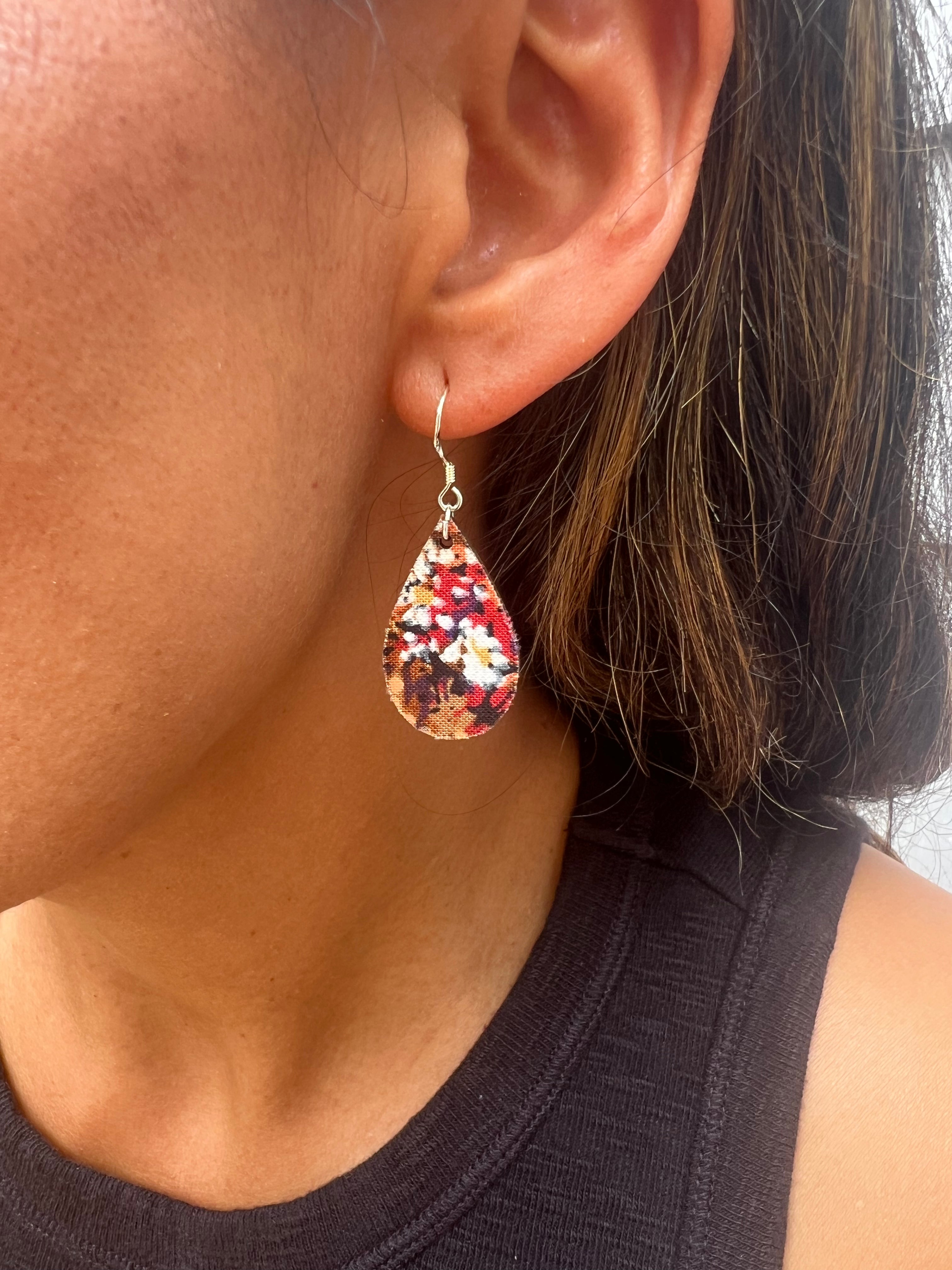 Close-up of a person wearing a colorful teardrop earring.