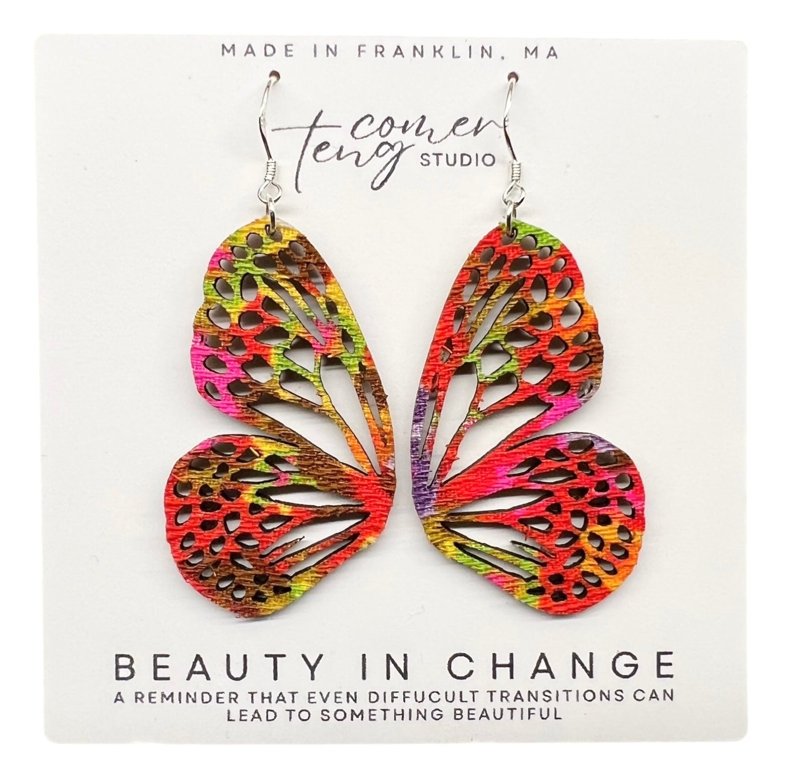 Colorful butterfly-shaped earrings on a card with branding and text.