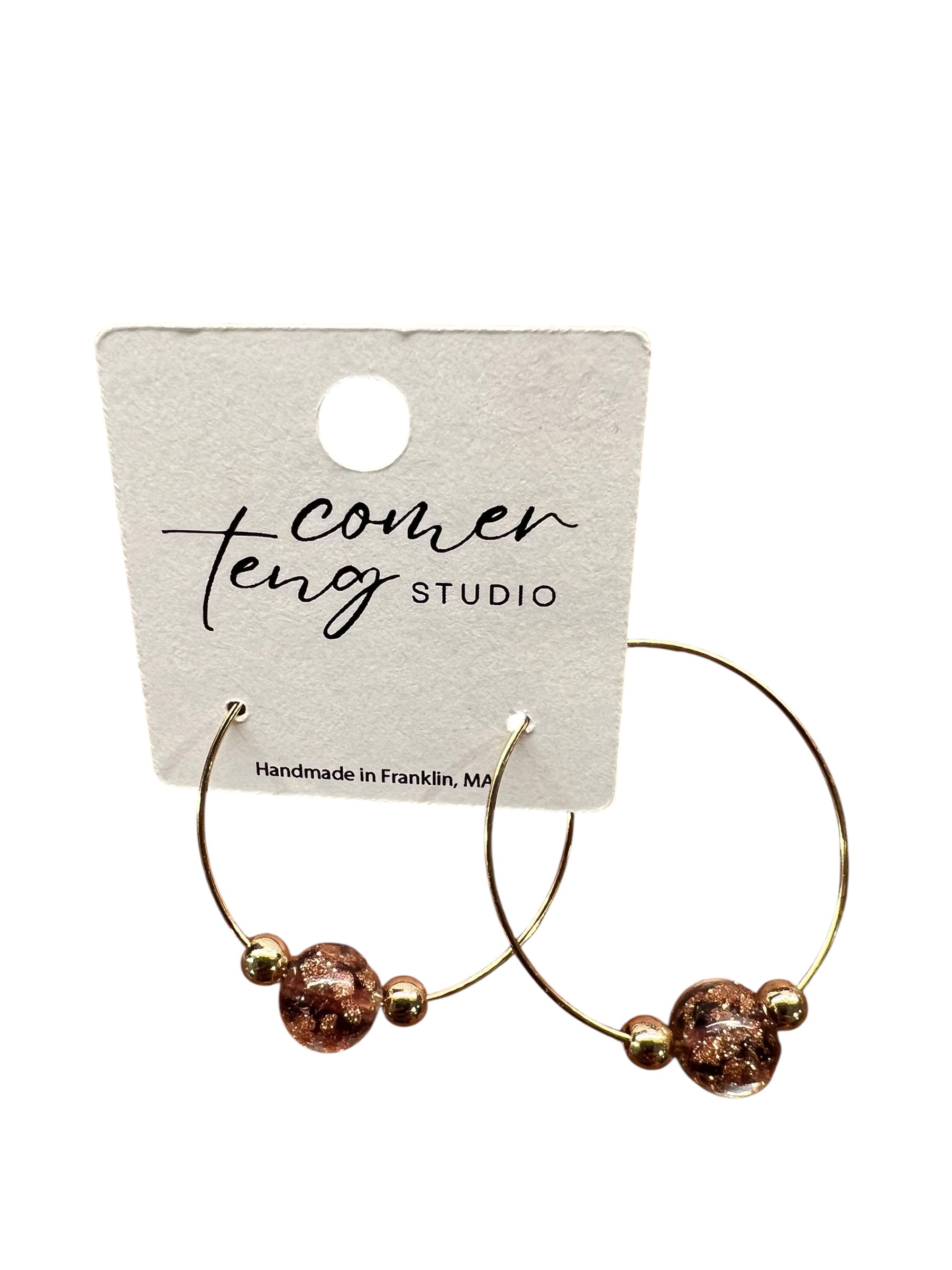 Gold hoop earrings with beads on a branded card.