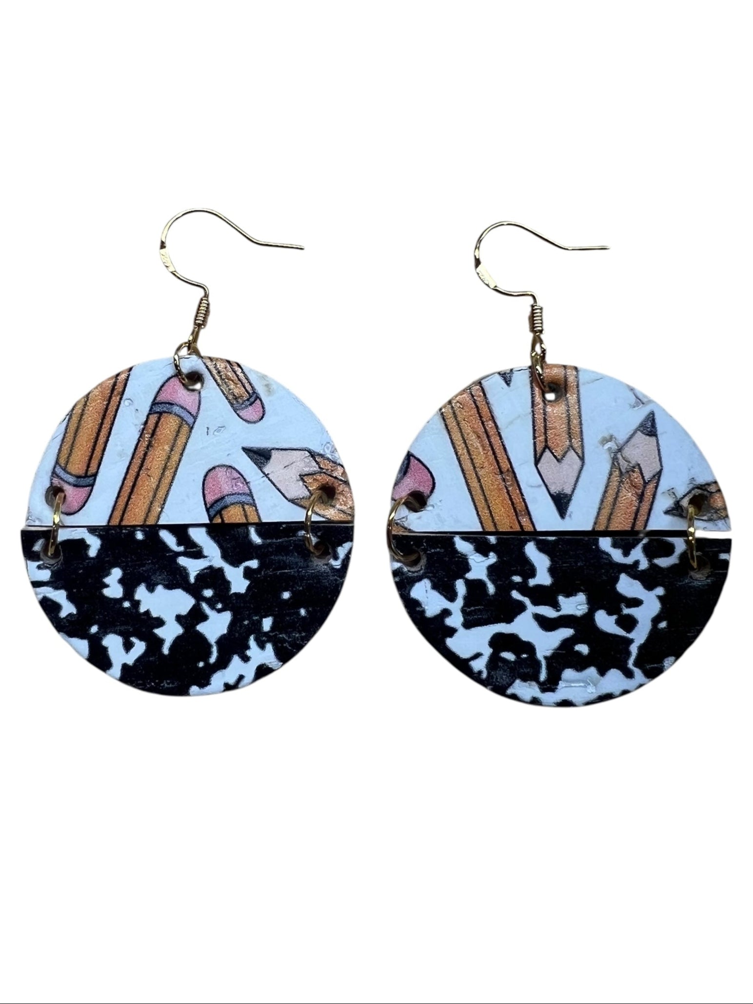 Round earrings with a split design featuring a pattern of pencils and composition cover on a white background.