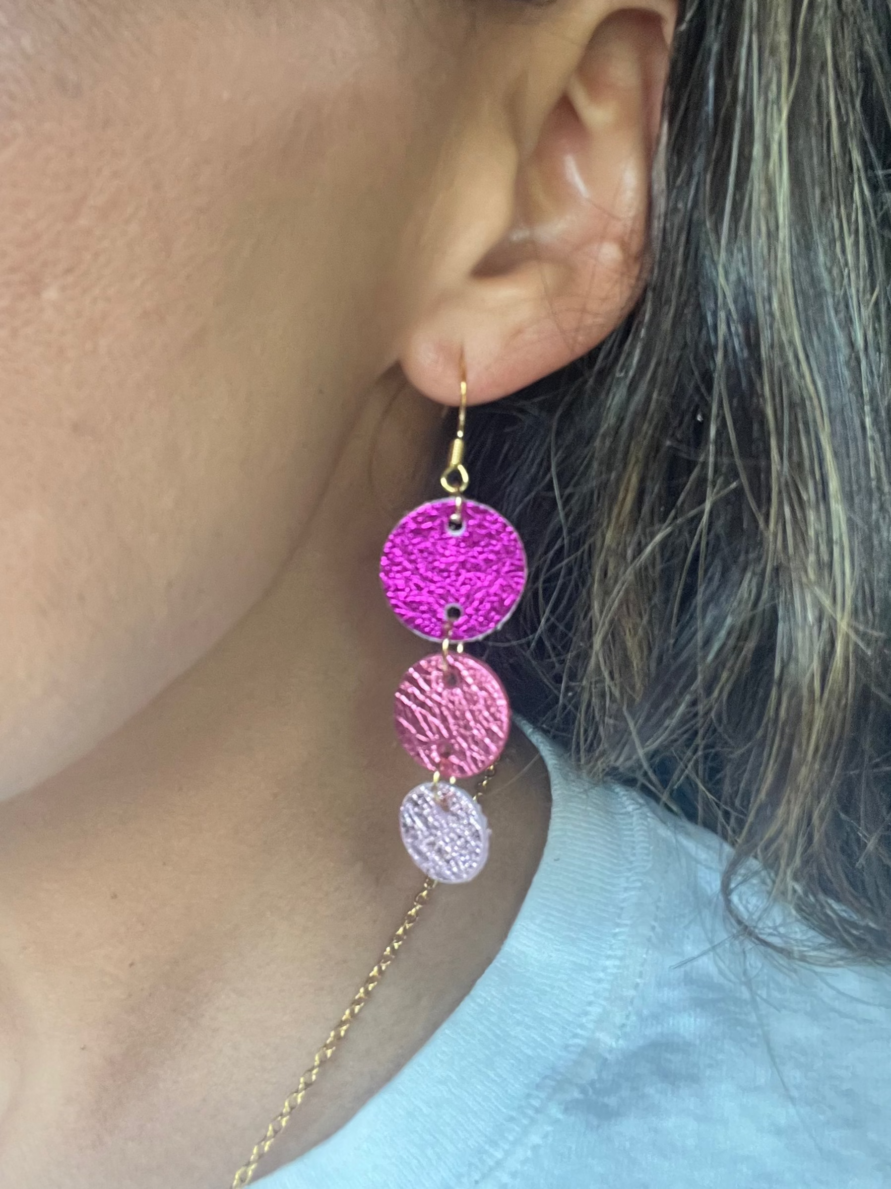 Close-up of a person wearing pink and gold earrings.
