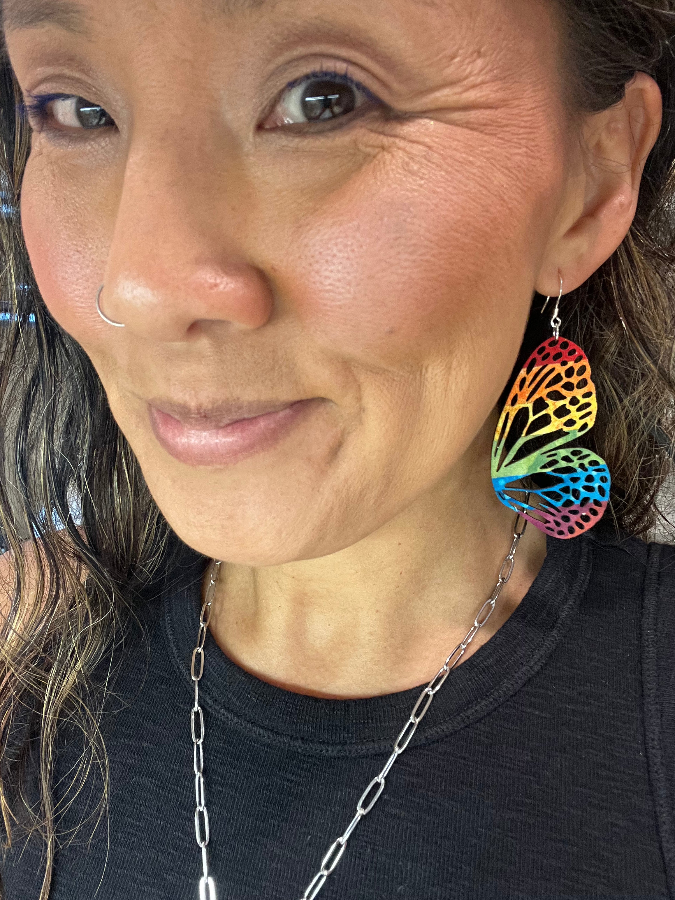 Close-up of a woman wearing colorful earrings and a black top.