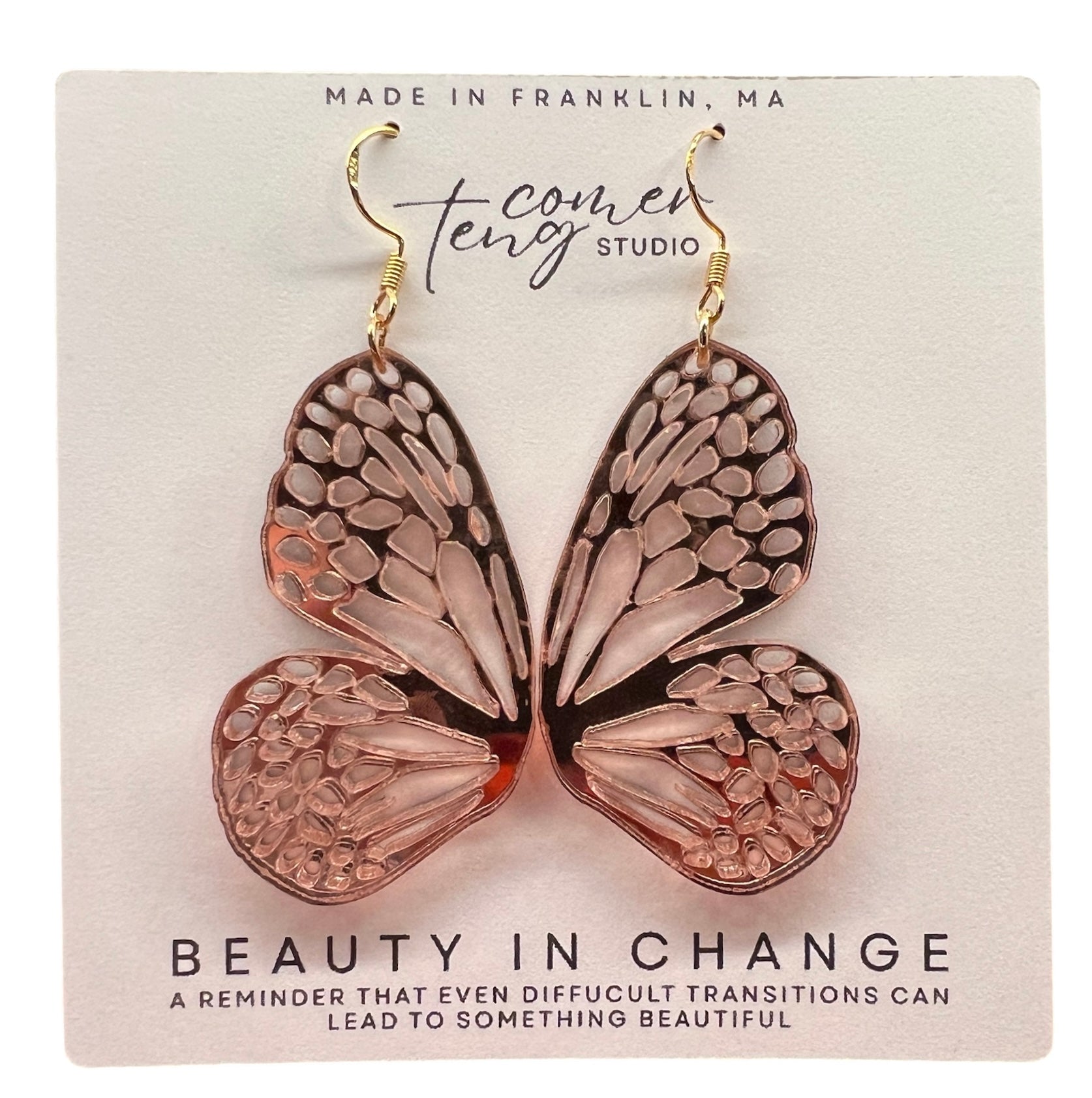 Butterfly-shaped earrings on a card with branding and text.