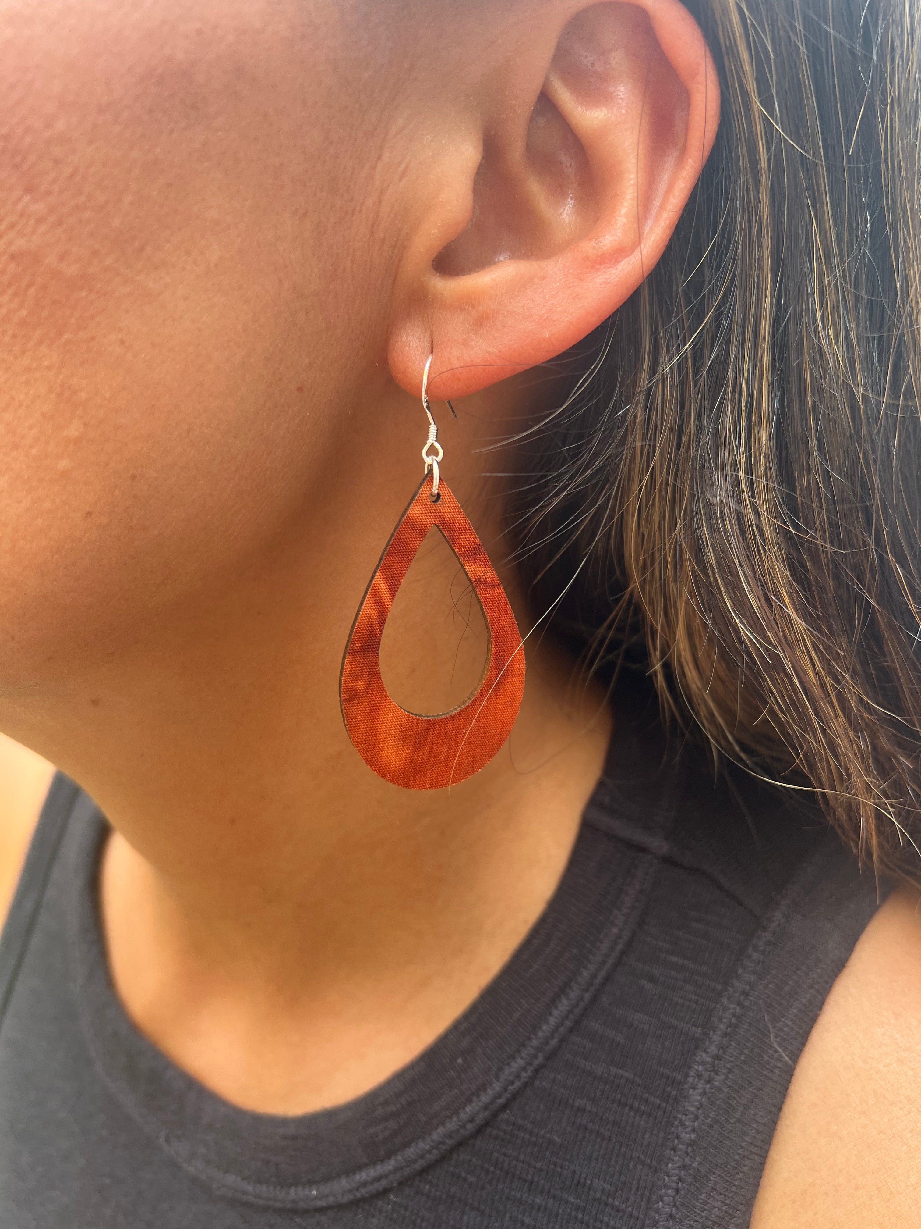 Teardrop-shaped earrings worn by a person with a neutral background