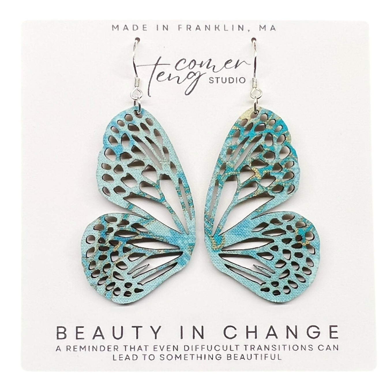 Turquoise butterfly-shaped earrings on a white card with text about beauty and change.