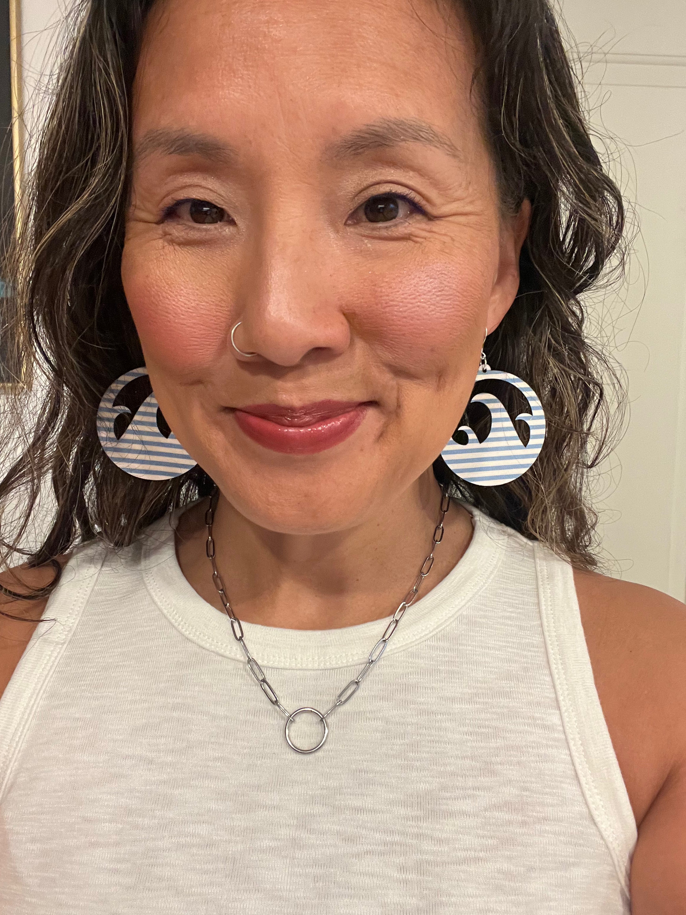 Woman wearing large circular earrings with striped patterns.