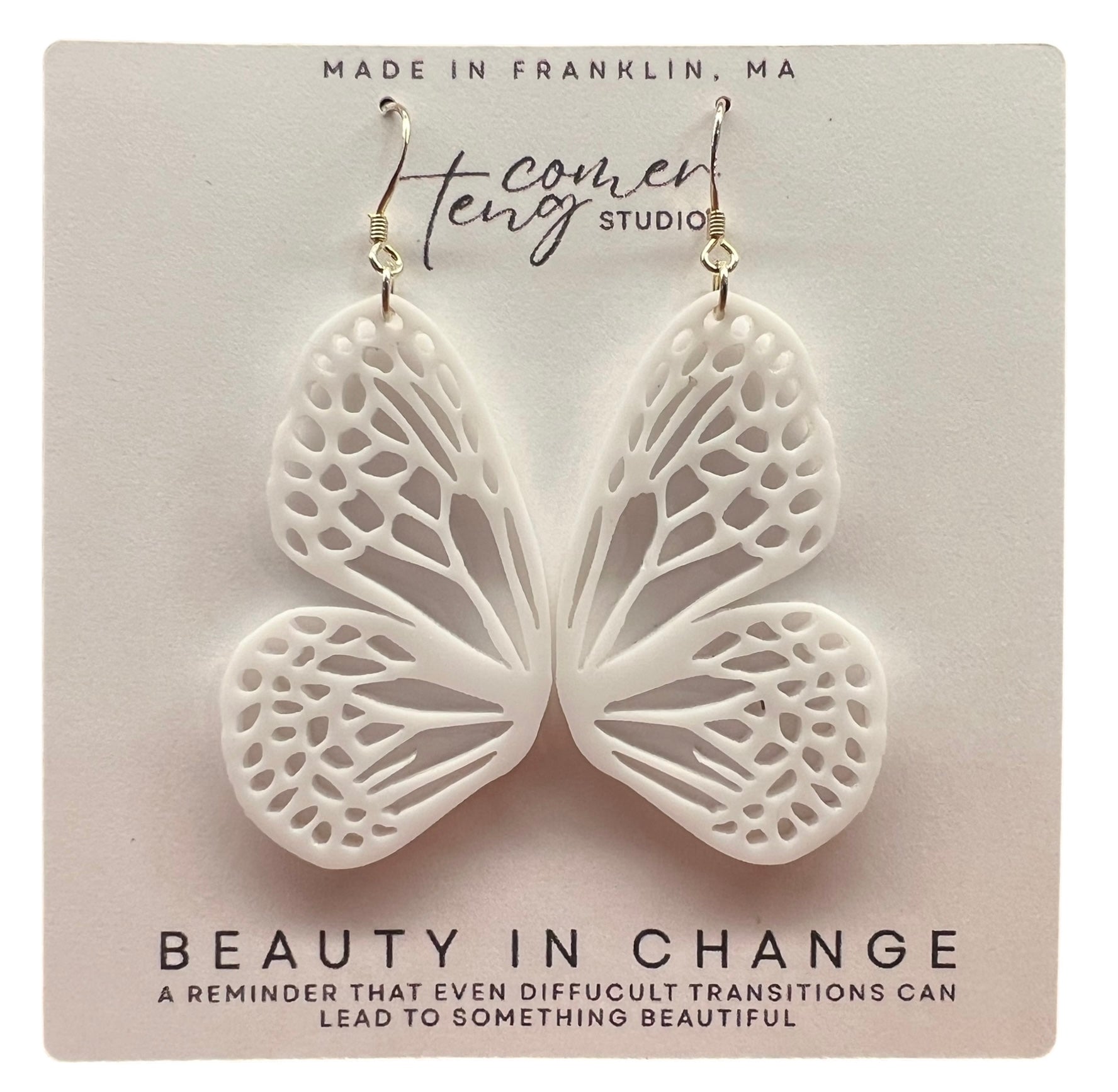 Butterfly-shaped earrings on a card with branding and text.