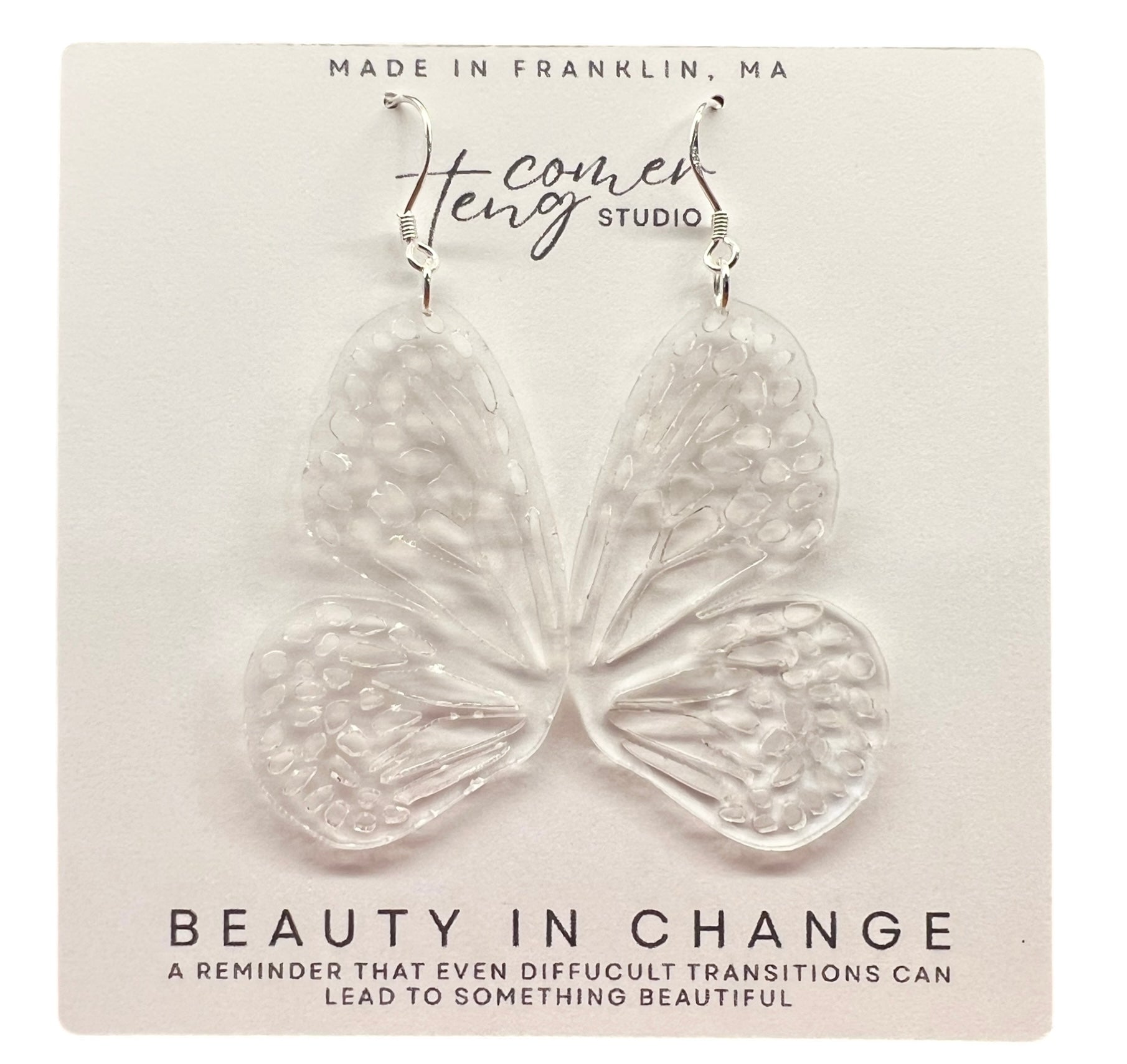 Butterfly-shaped earrings on a card with branding and text.