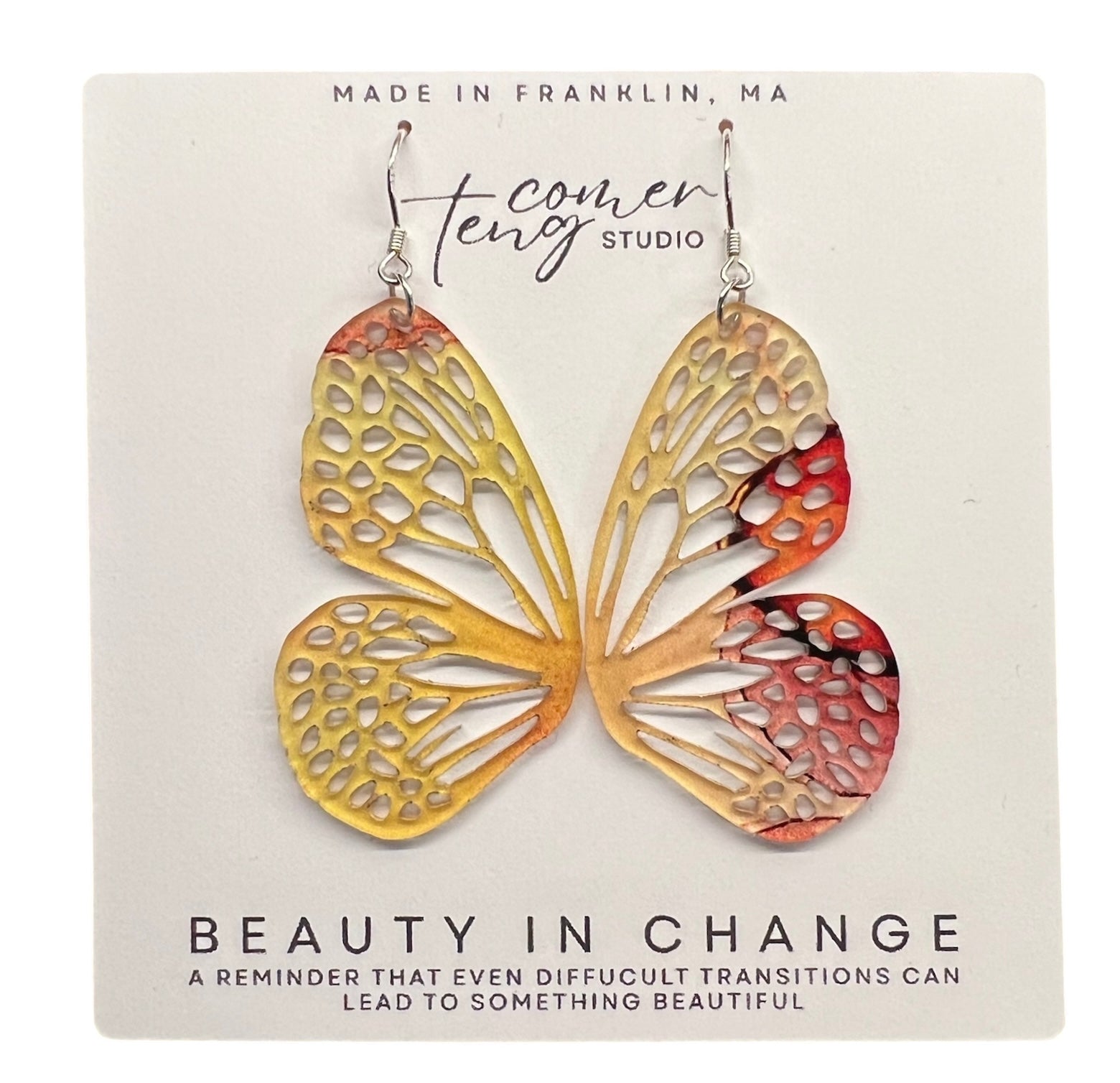 Butterfly-shaped earrings on a card with branding and motivational text.