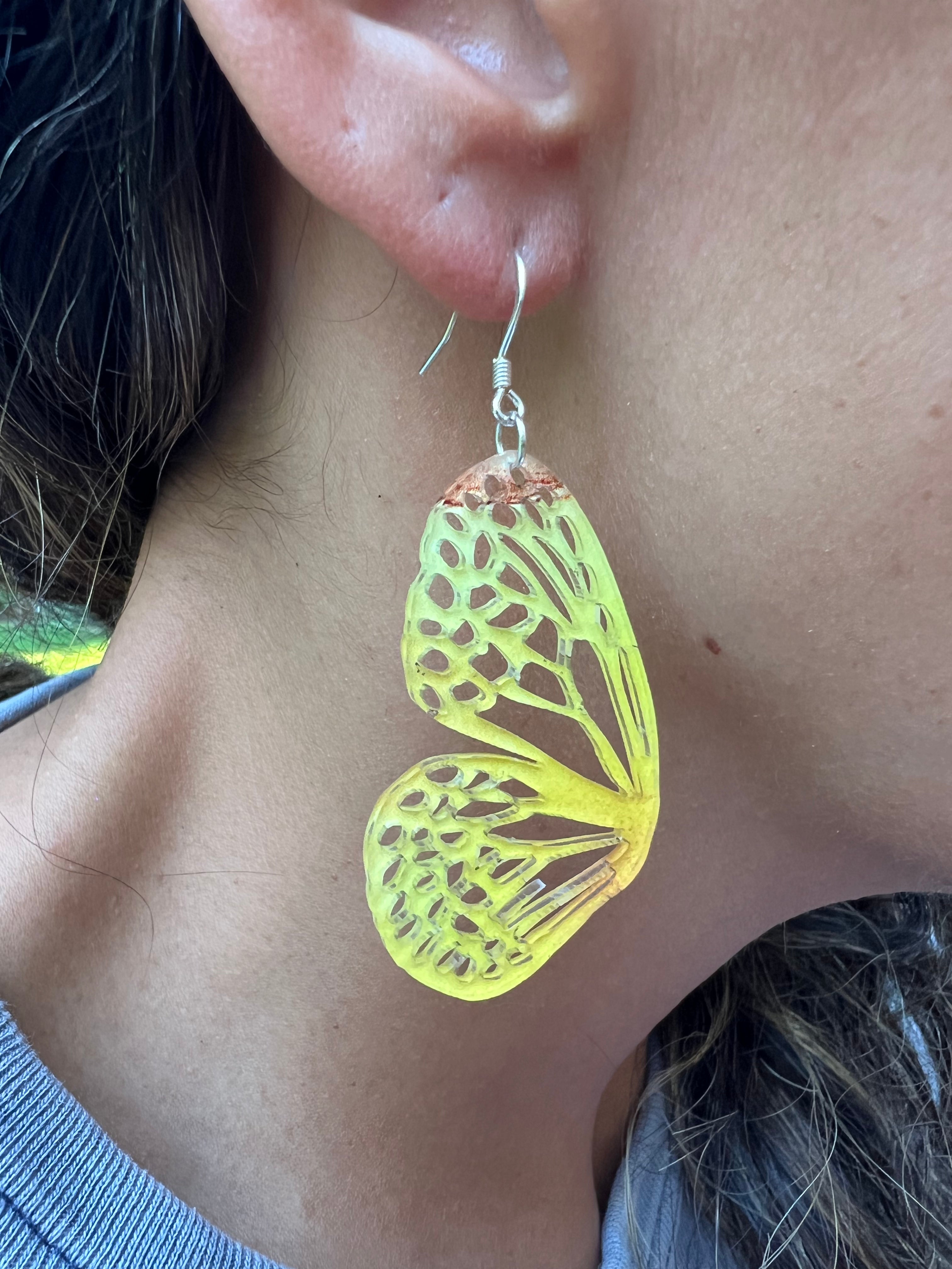 Yellow butterfly-shaped earrings being worn on an ear