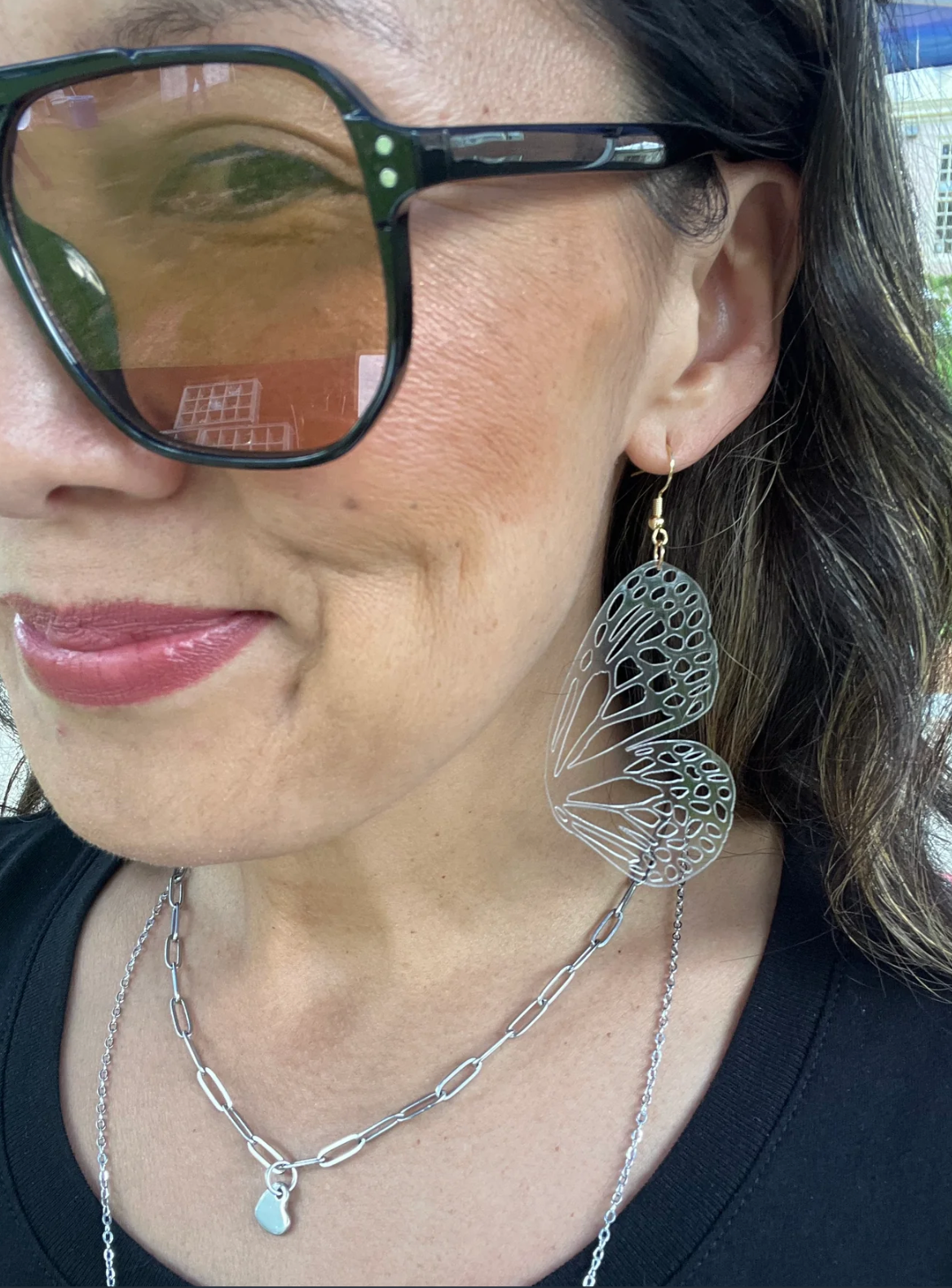 Close-up of a person wearing butterfly-shaped earrings and a necklace.